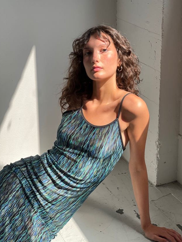 A model wearing the green naomi dress in an aesthetically background. 100% deadstock Missoni-like, polyester knit blend