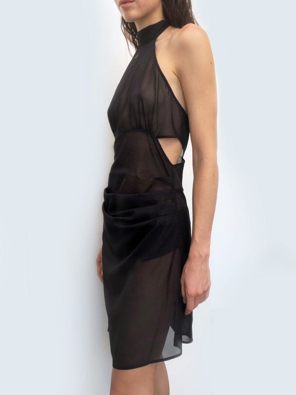 Black sheer dress with cutouts worn by a model against a plain background. Made from sustainable deadstock fabric.