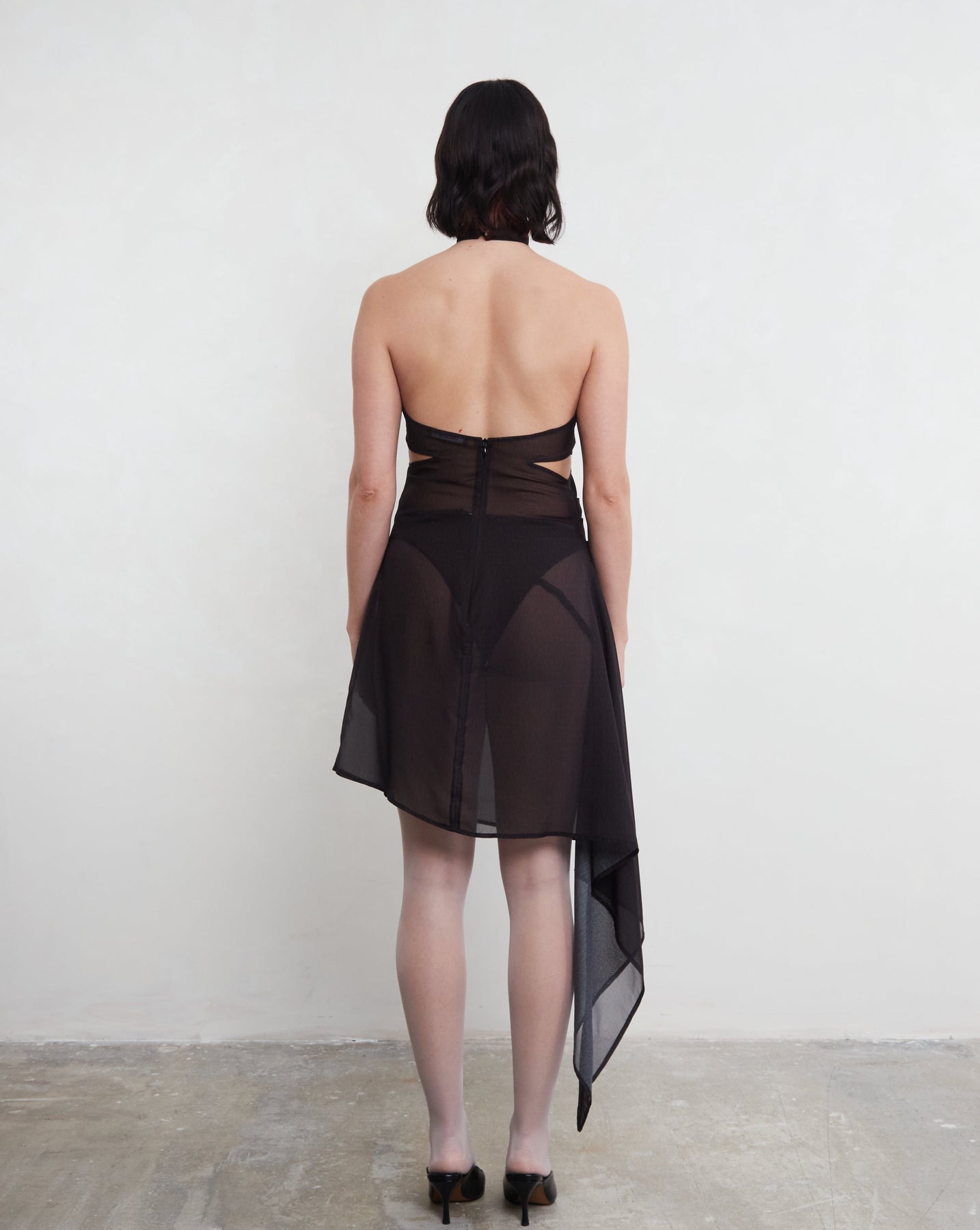 Model wearing a black deadstock dress with a sheer back panel against a white background.