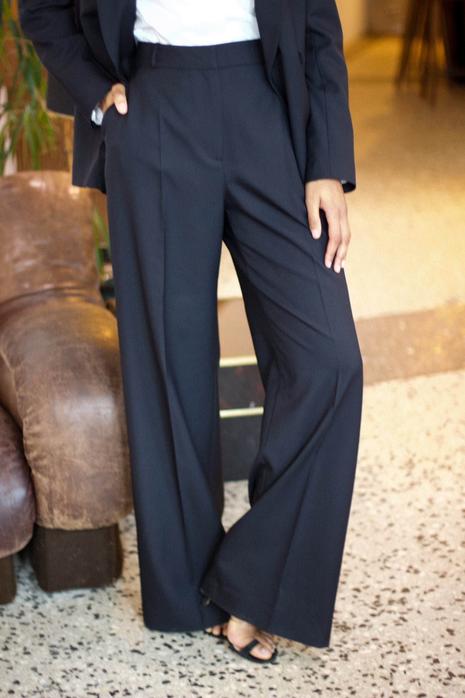 Close-up of a model wearing the bianca charcoal wool pants in an aesthetically background. 100% made from upcycled wool.