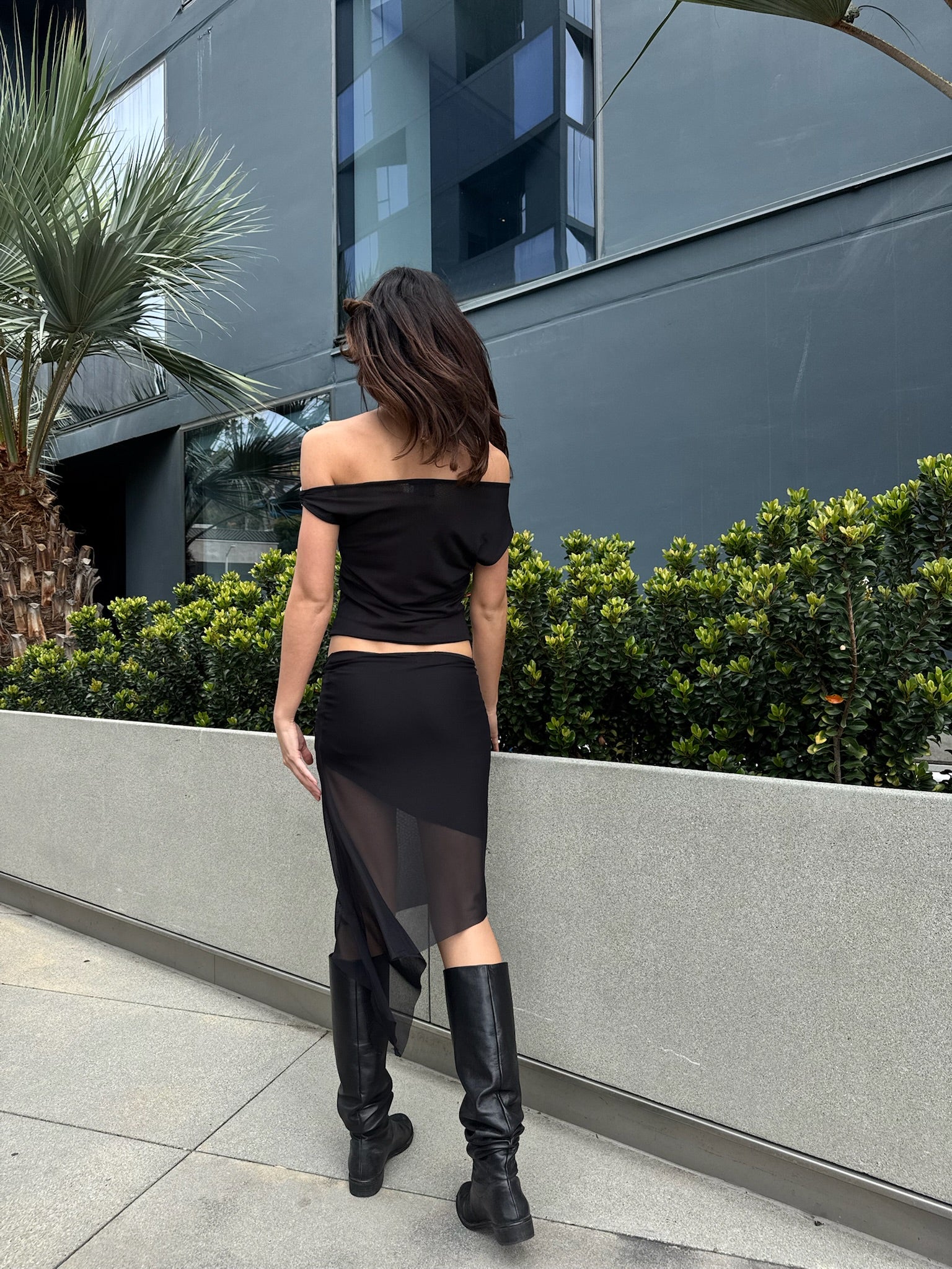 A model wearing the black city skirt in an aesthetically background. 100% made from sustainable deadstock materials.