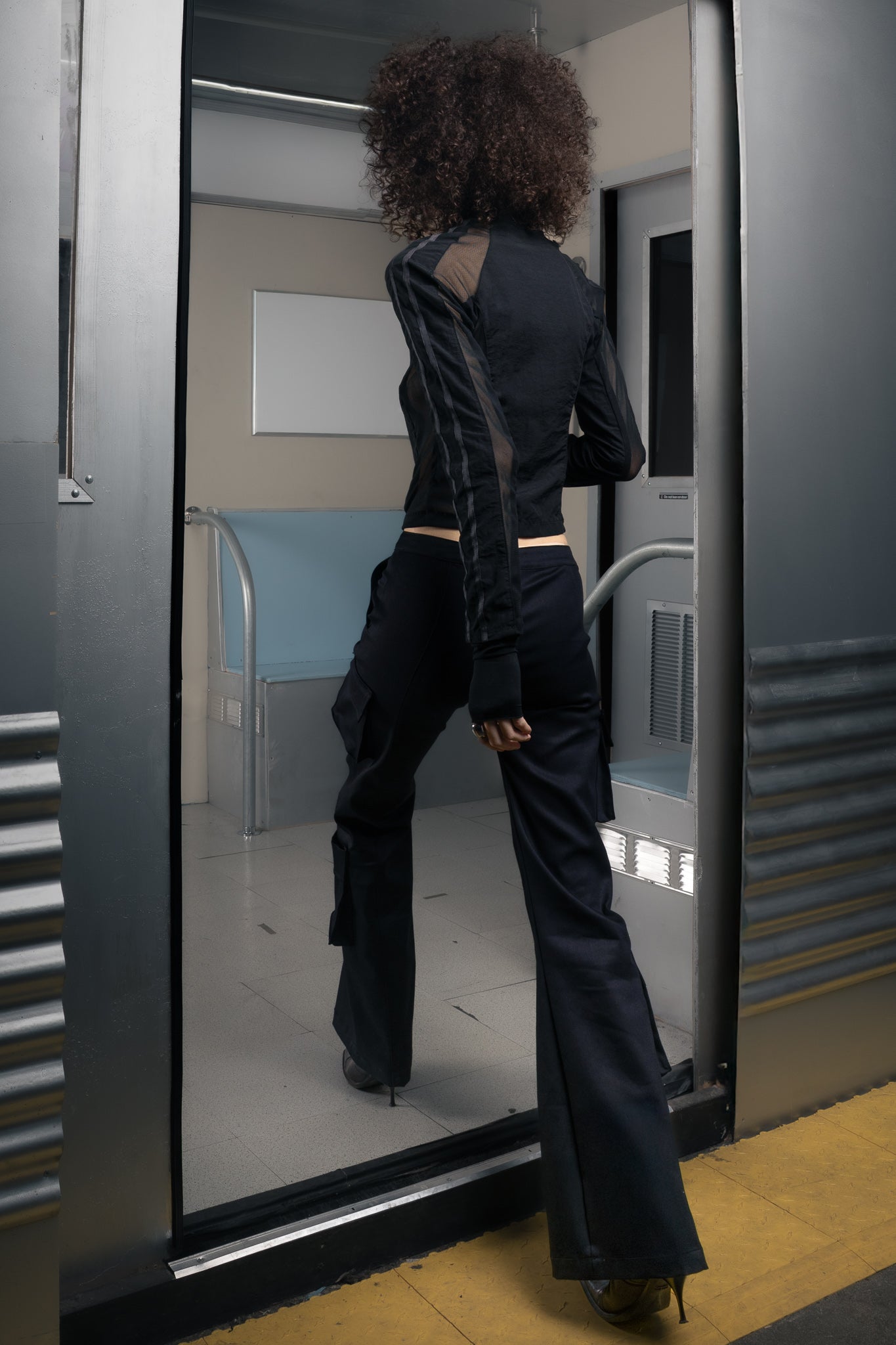 Woman wearing a sustainable black outfit walking into a futuristic train