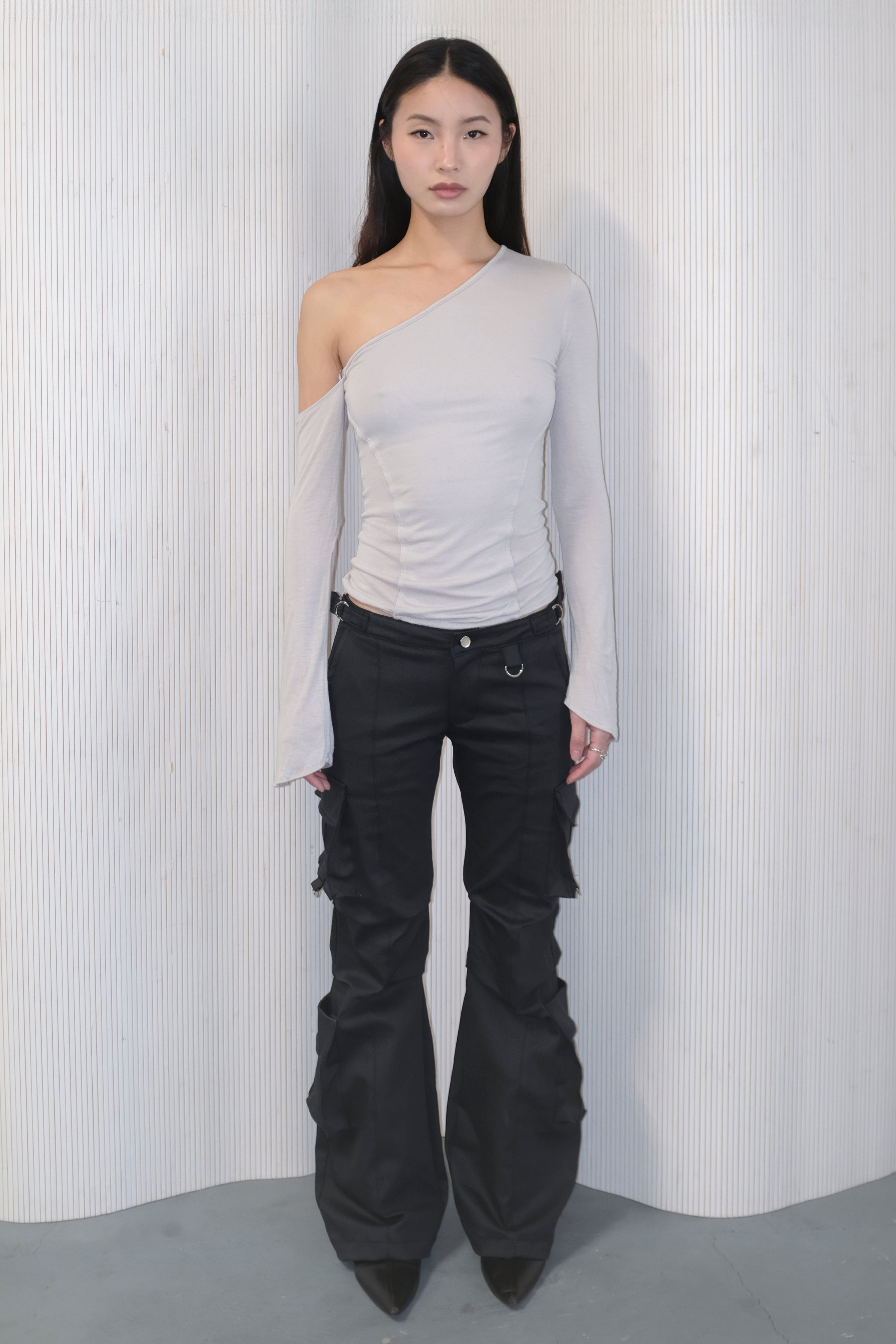 A model wearing the bootcut cargo pants in an aesthetically background. 100% deadstock, in a breathable cotton-poly twill.