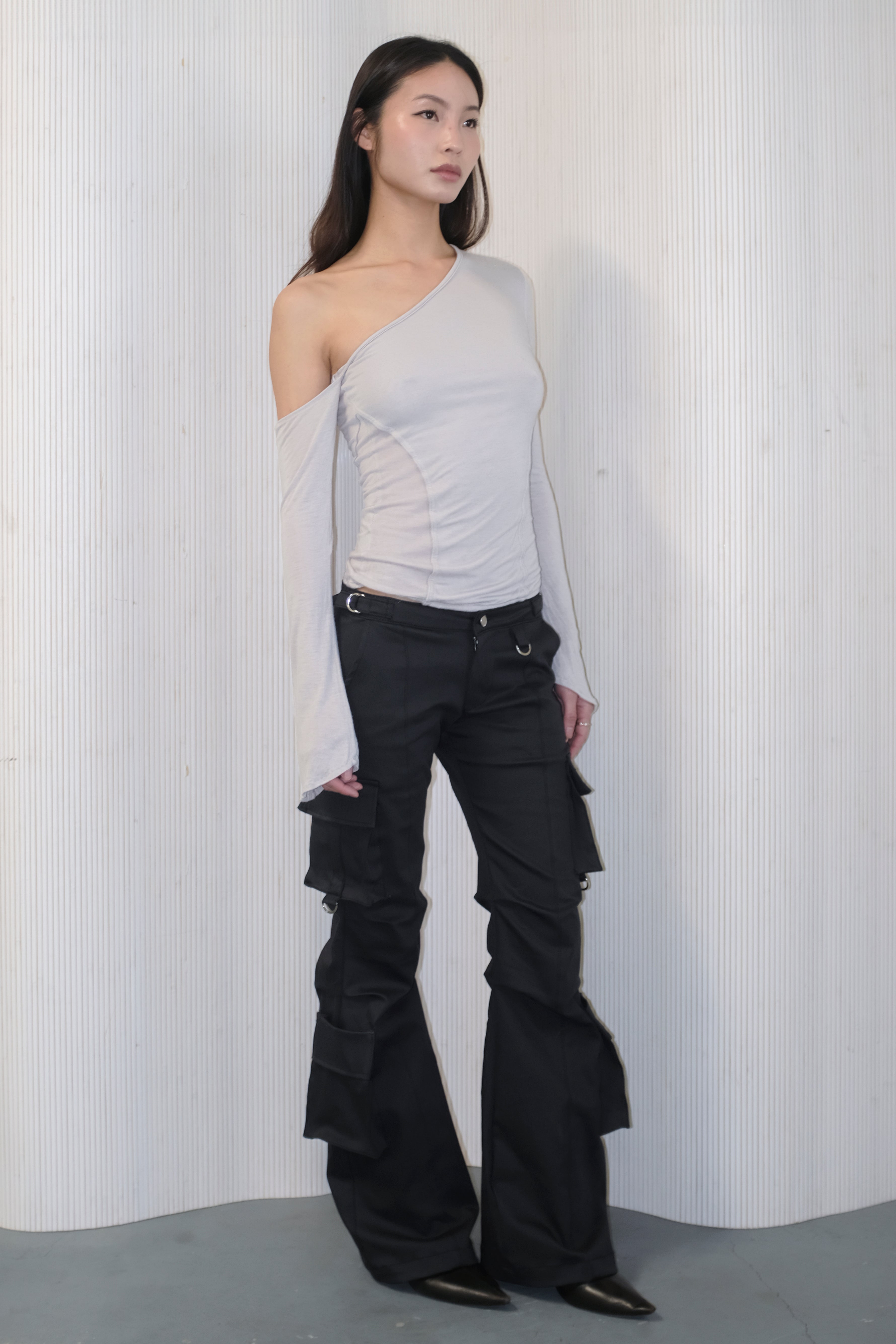 A model wearing the bootcut cargo pants in an aesthetically background. 100% deadstock, in a breathable cotton-poly twill.