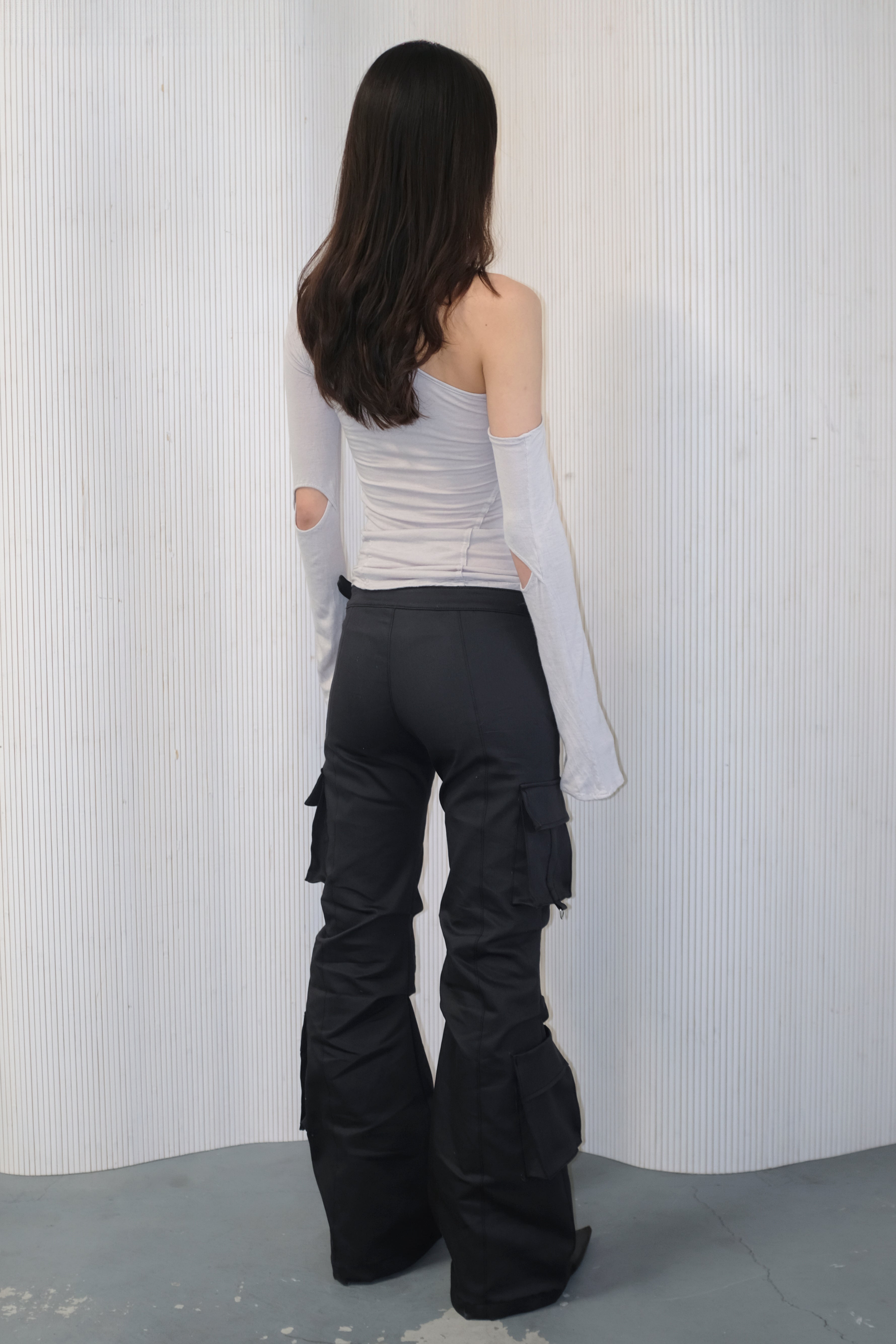 A model wearing the bootcut cargo pants in an aesthetically background. 100% deadstock, in a breathable cotton-poly twill.