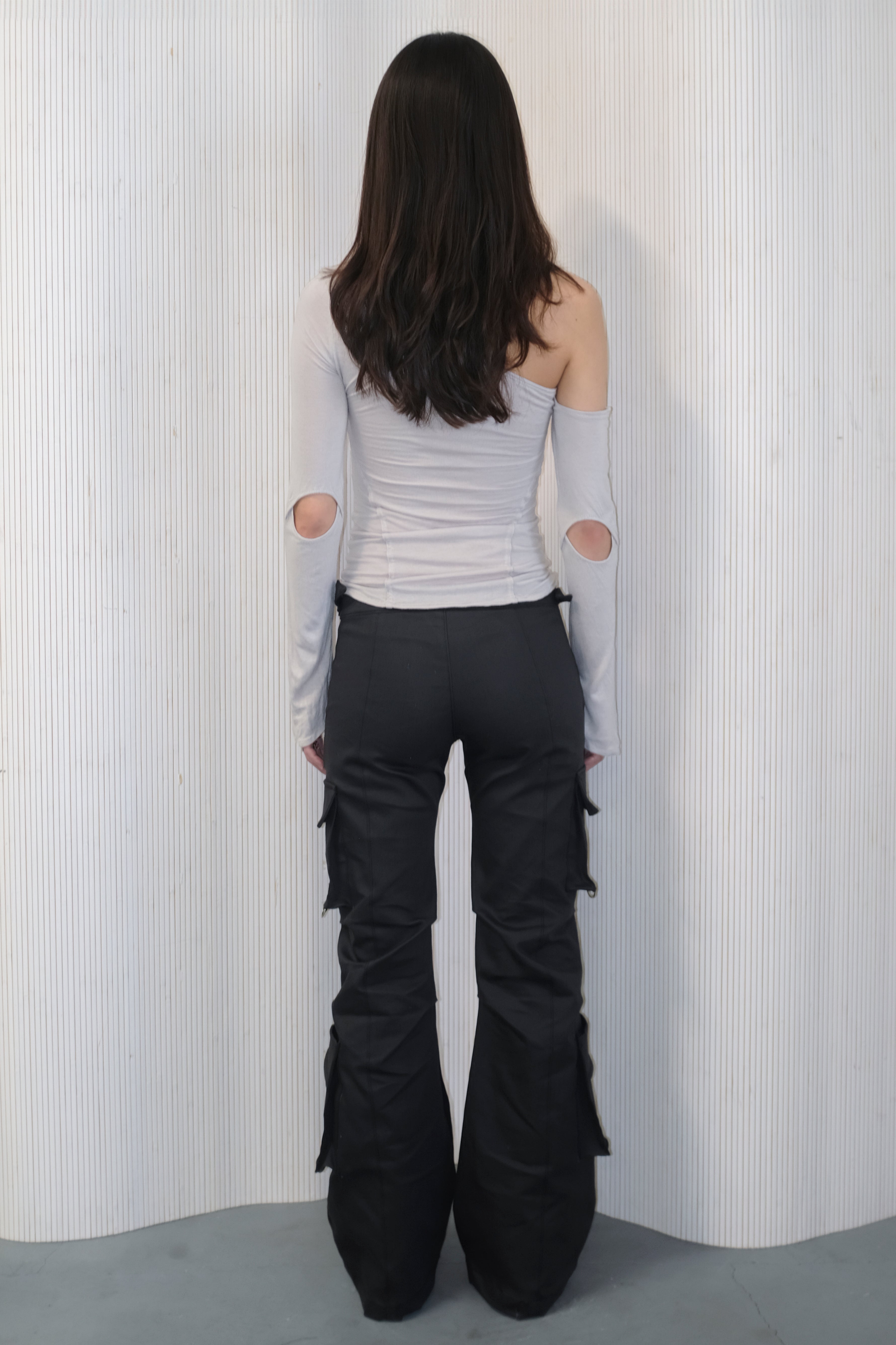 A model wearing the bootcut cargo pants in an aesthetically background. 100% deadstock, in a breathable cotton-poly twill.