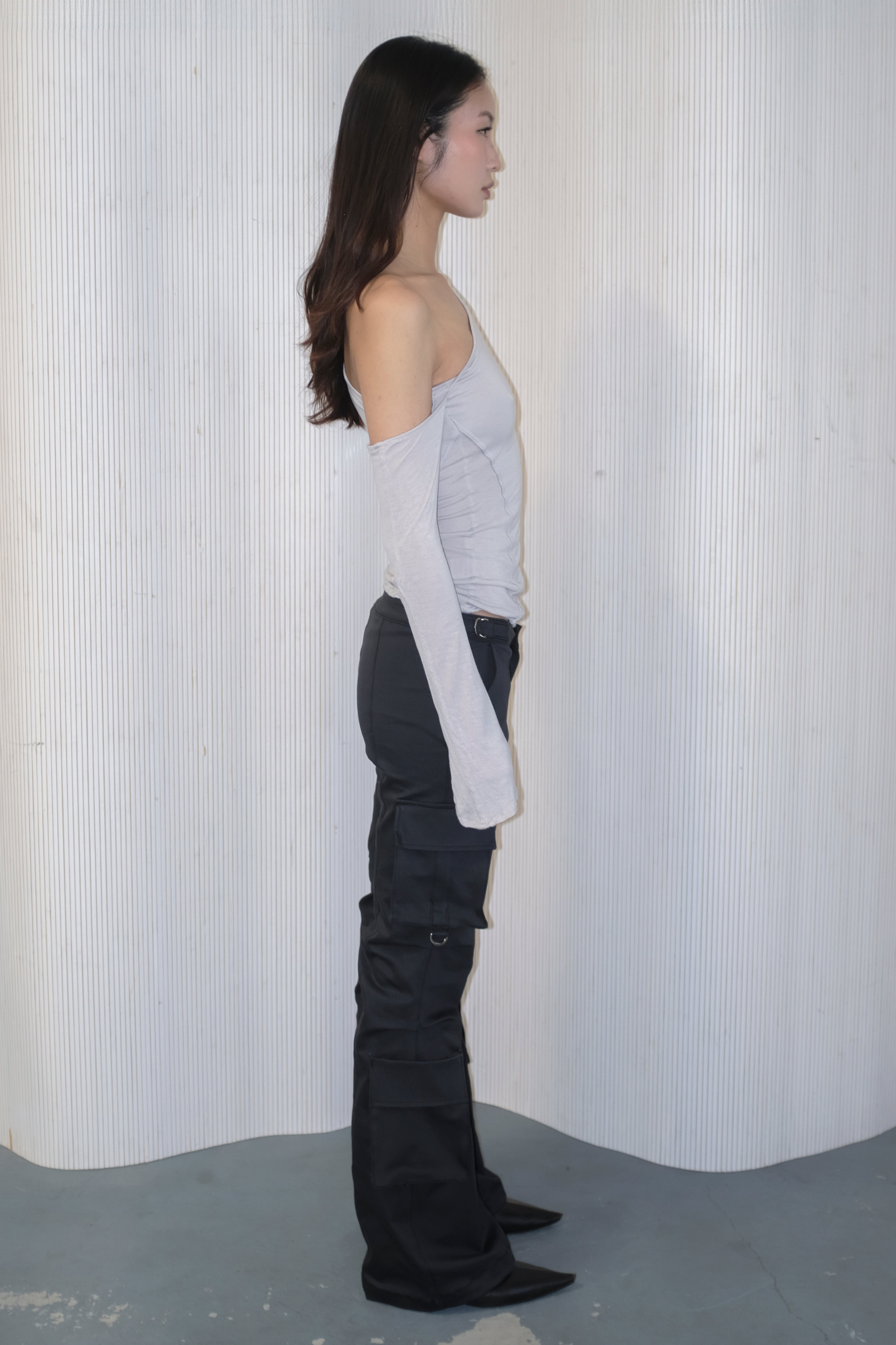 A model wearing the bootcut cargo pants in an aesthetically background. 100% deadstock, in a breathable cotton-poly twill.