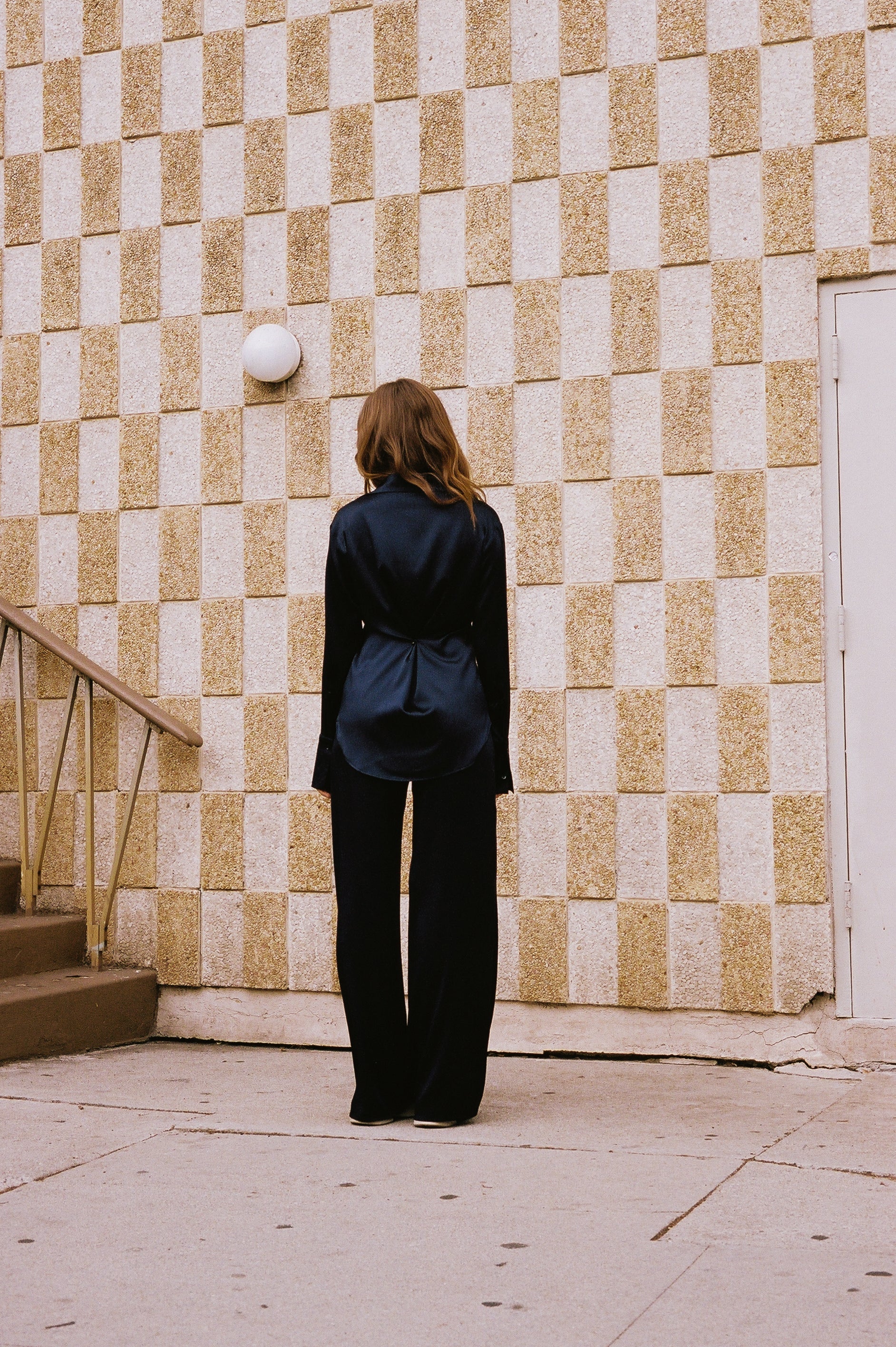 girl standing up wearing roma silk pants and borro silk button up in navy