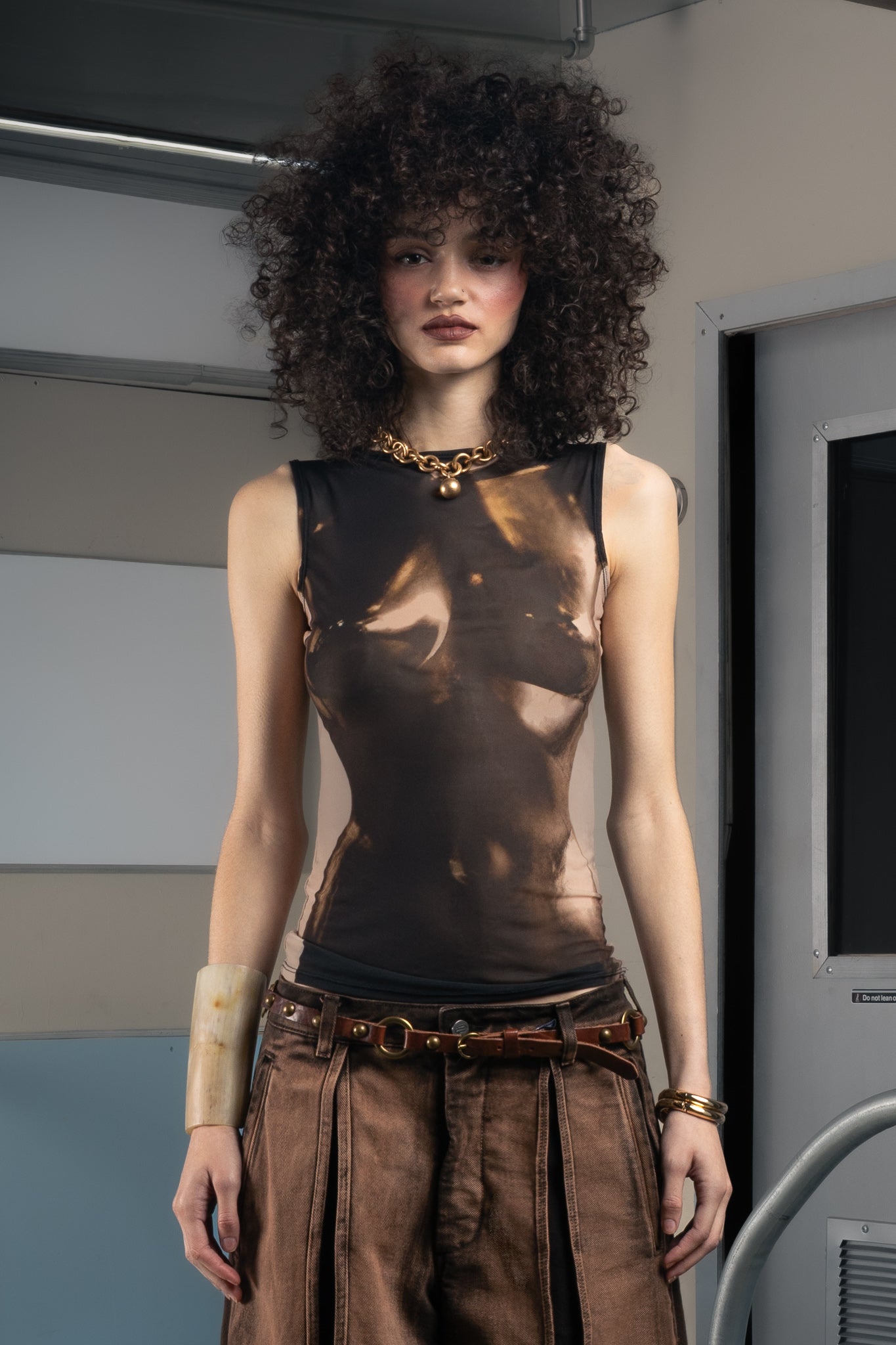 Woman wearing a sustainable black sleeveless top and brown pants in a futuristic setting