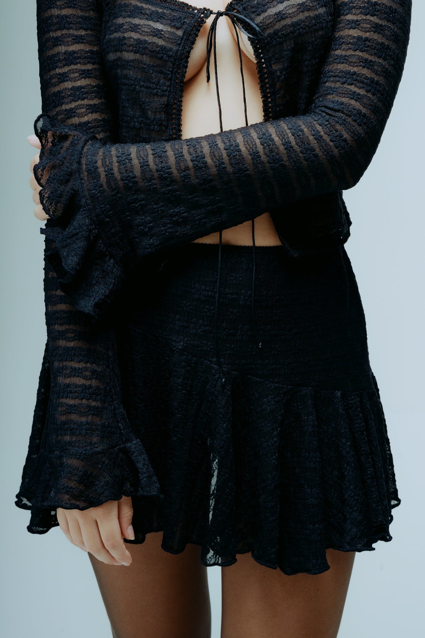 A model wearing the dreamwave mini skirt in a white background. 100% deadstock lace material. CLOSE UP