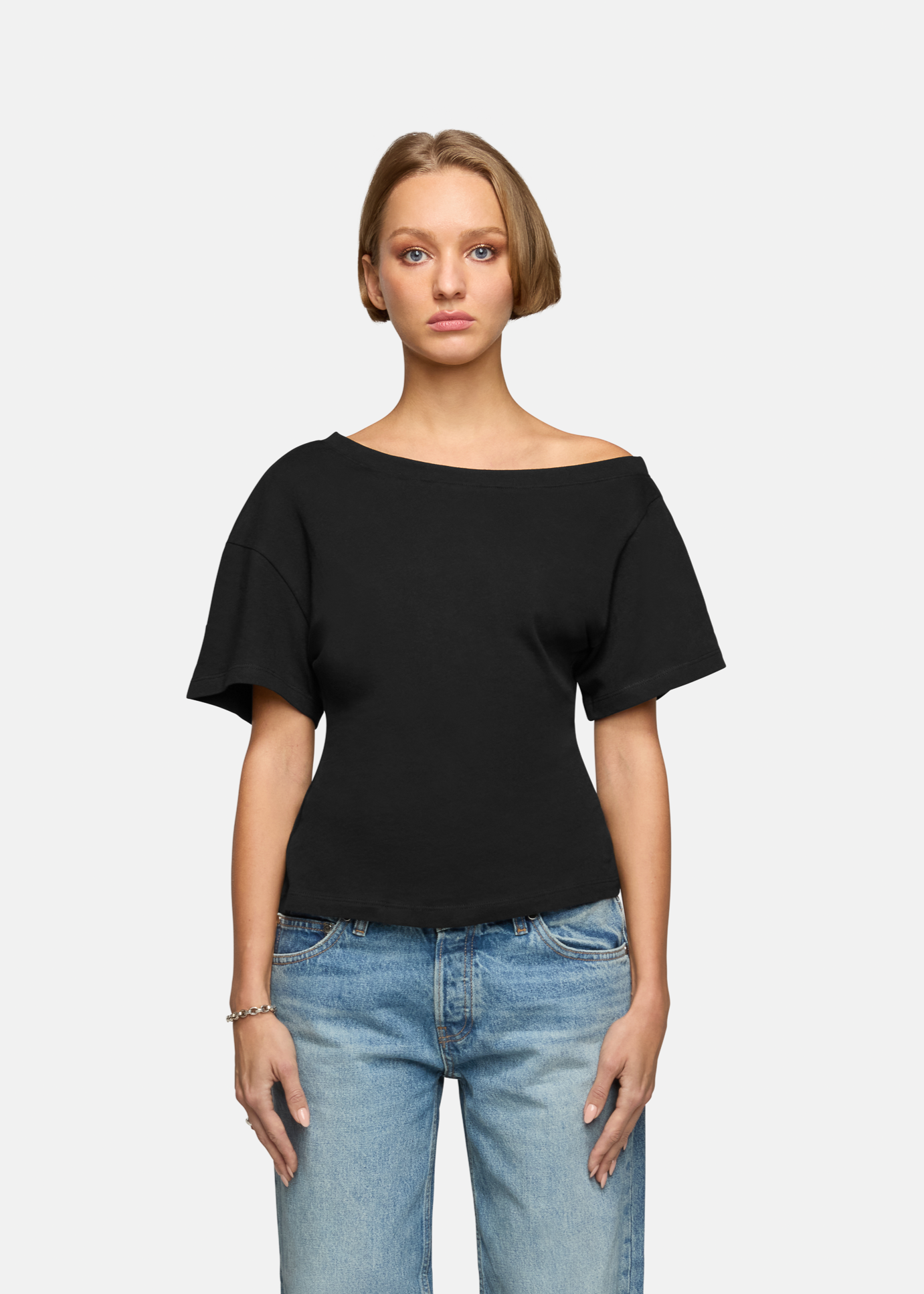 A model wearing the black elena off shoulder tee in a white background. 100% made from cotton.