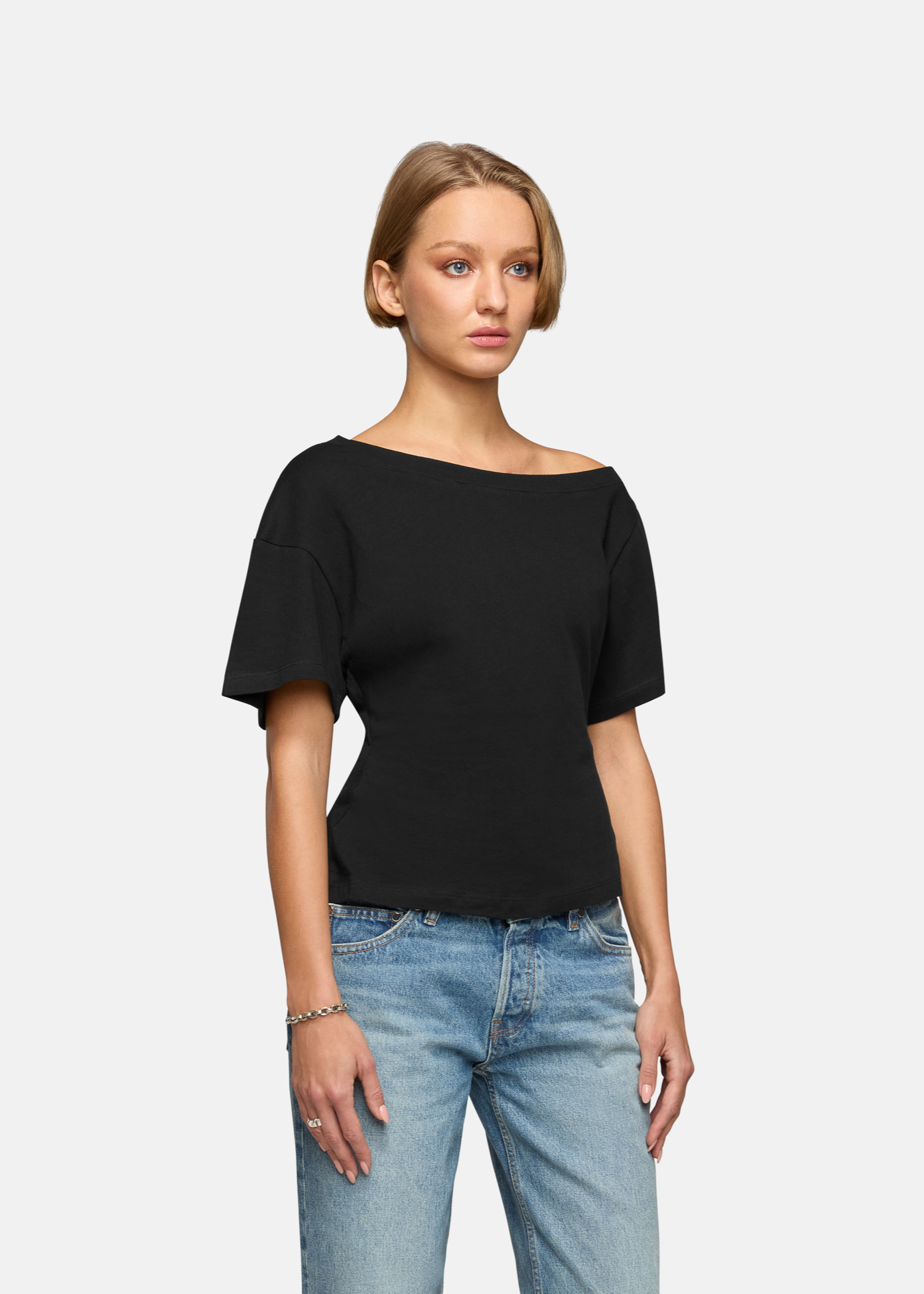 A model wearing the black elena off shoulder tee in a white background. 100% made from cotton.