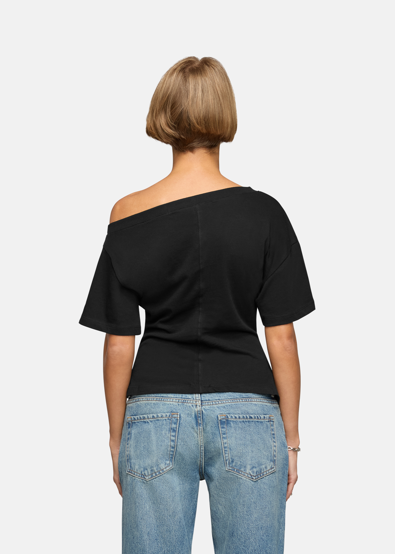 A model wearing the black elena off shoulder tee in a white background. 100% made from cotton.