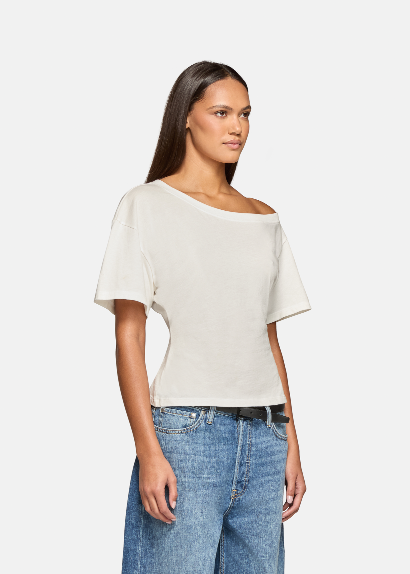 A model wearing the white elena off shoulder tee in a white background. 100% made from cotton.