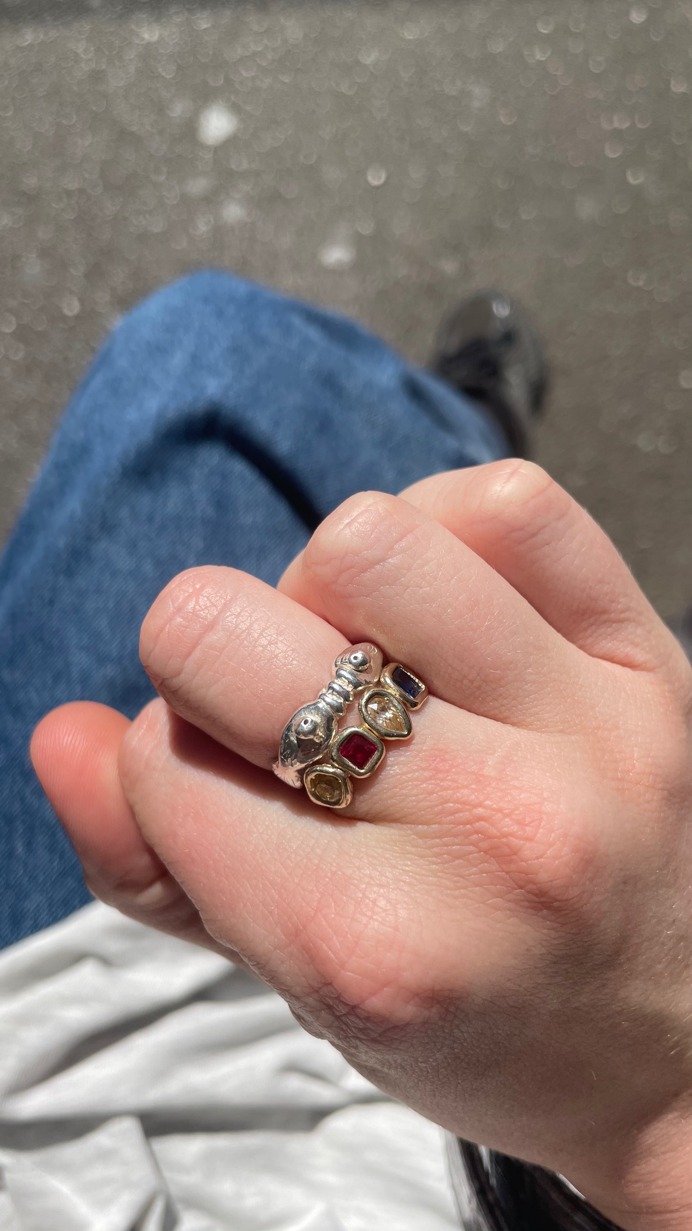 A hand model wearing the kissing fish ring. Made from 100% recycled metals and lab created gemstones. CLOSE UP