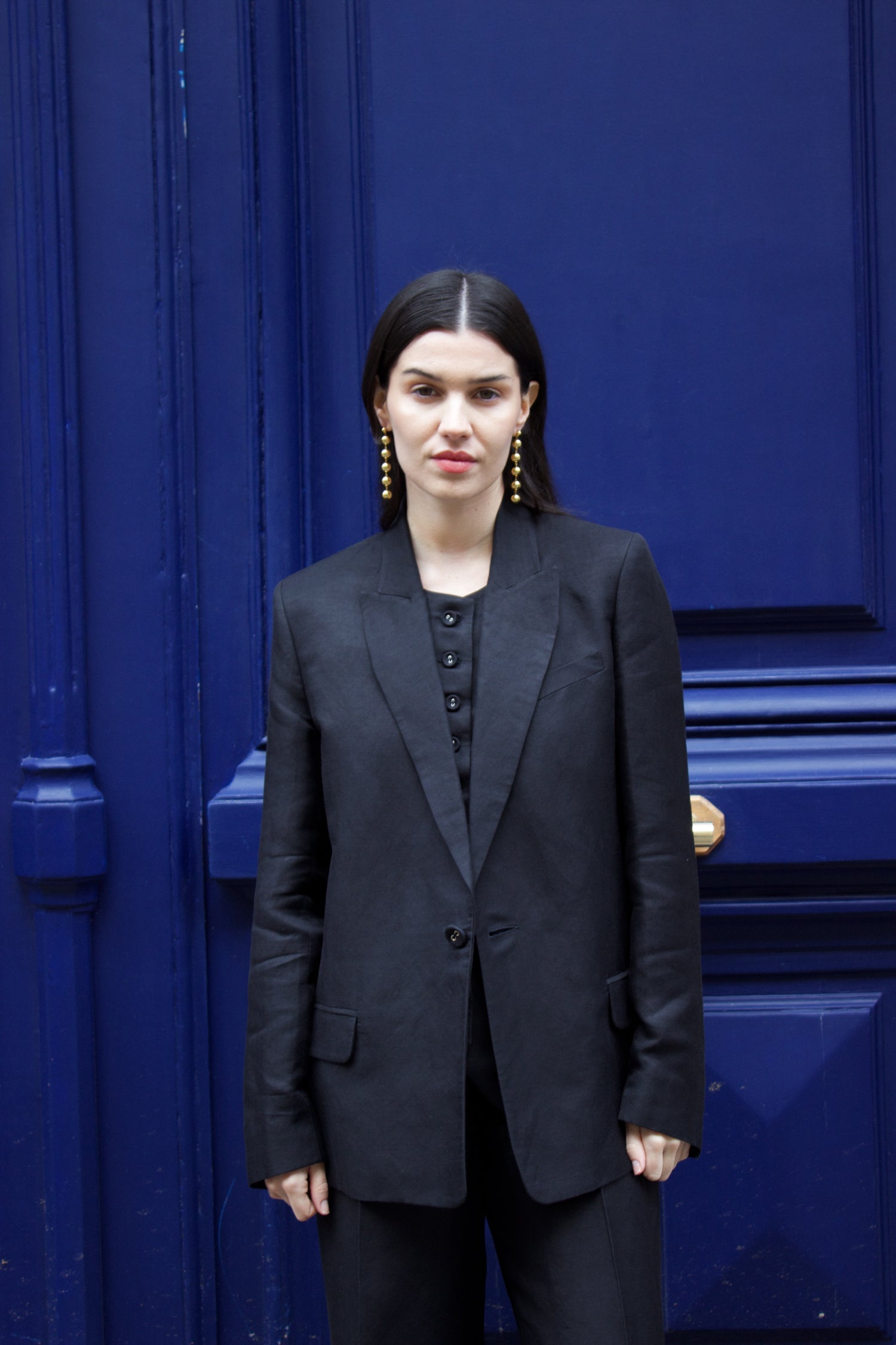 A model wearing the lauren black linen twill blazer in an aesthetically background. 100% upcycled GOTS certified linen.