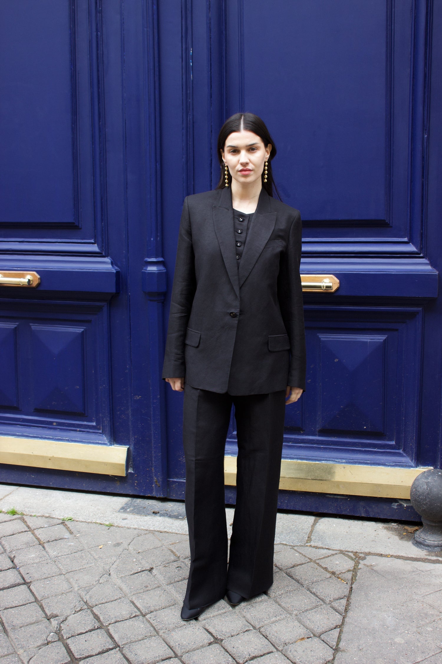 A model wearing the lauren black linen twill blazer in an aesthetically background. 100% upcycled GOTS certified linen.