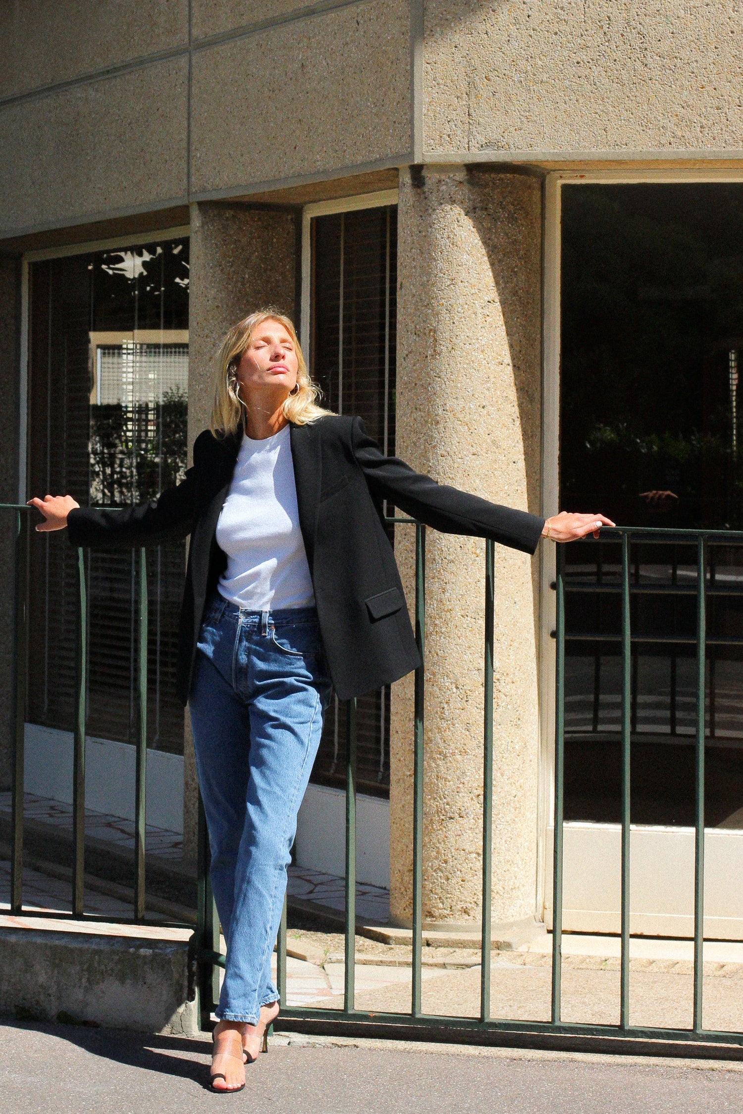 A model wearing the lauren black wool gabardine blazer in an aesthetically background. 100% made from sustainable upcycled wool.