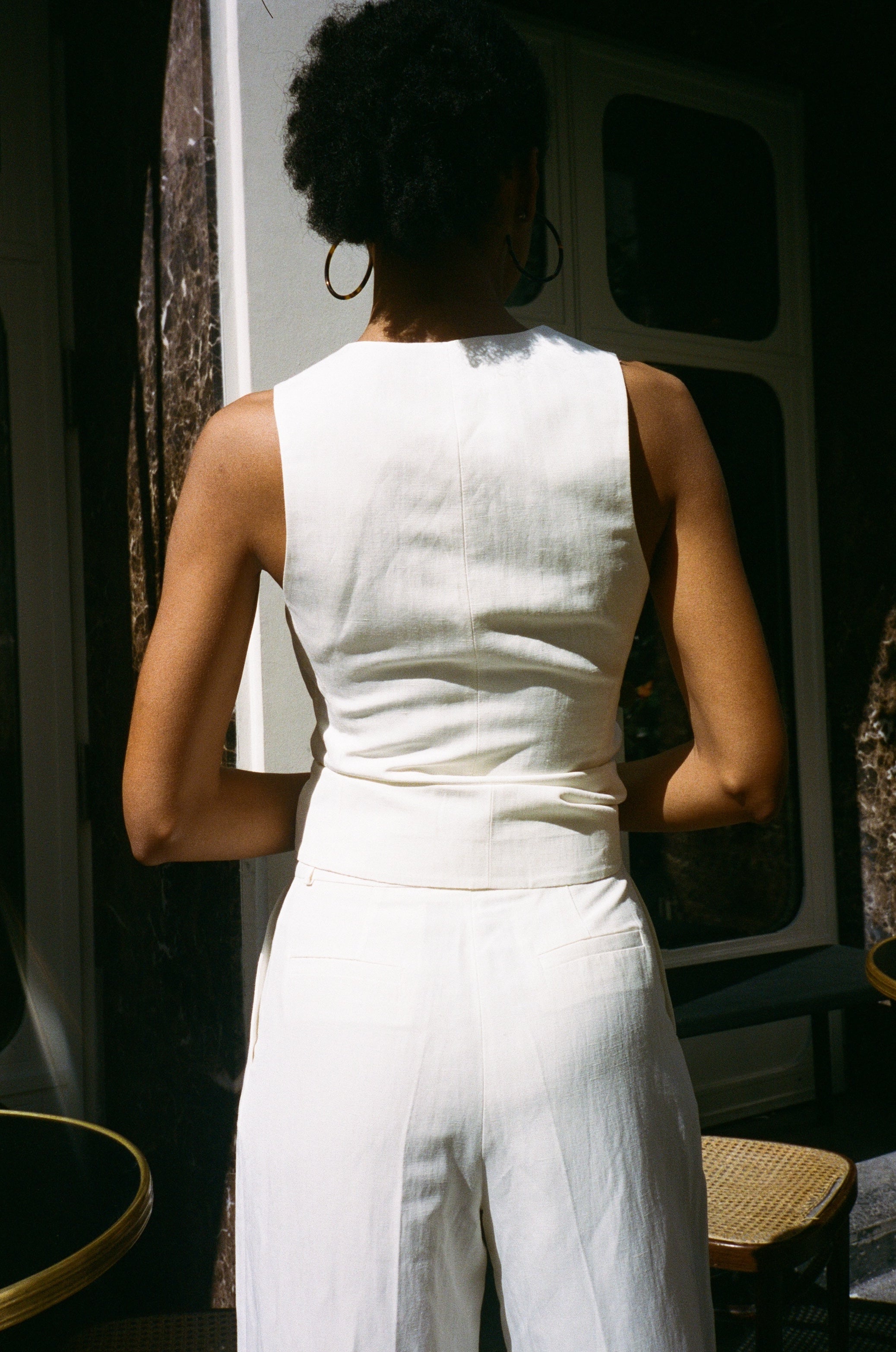 A model wearing the monica off white vest in an aestheticaly background. 100% upcycled linen and silk mix.