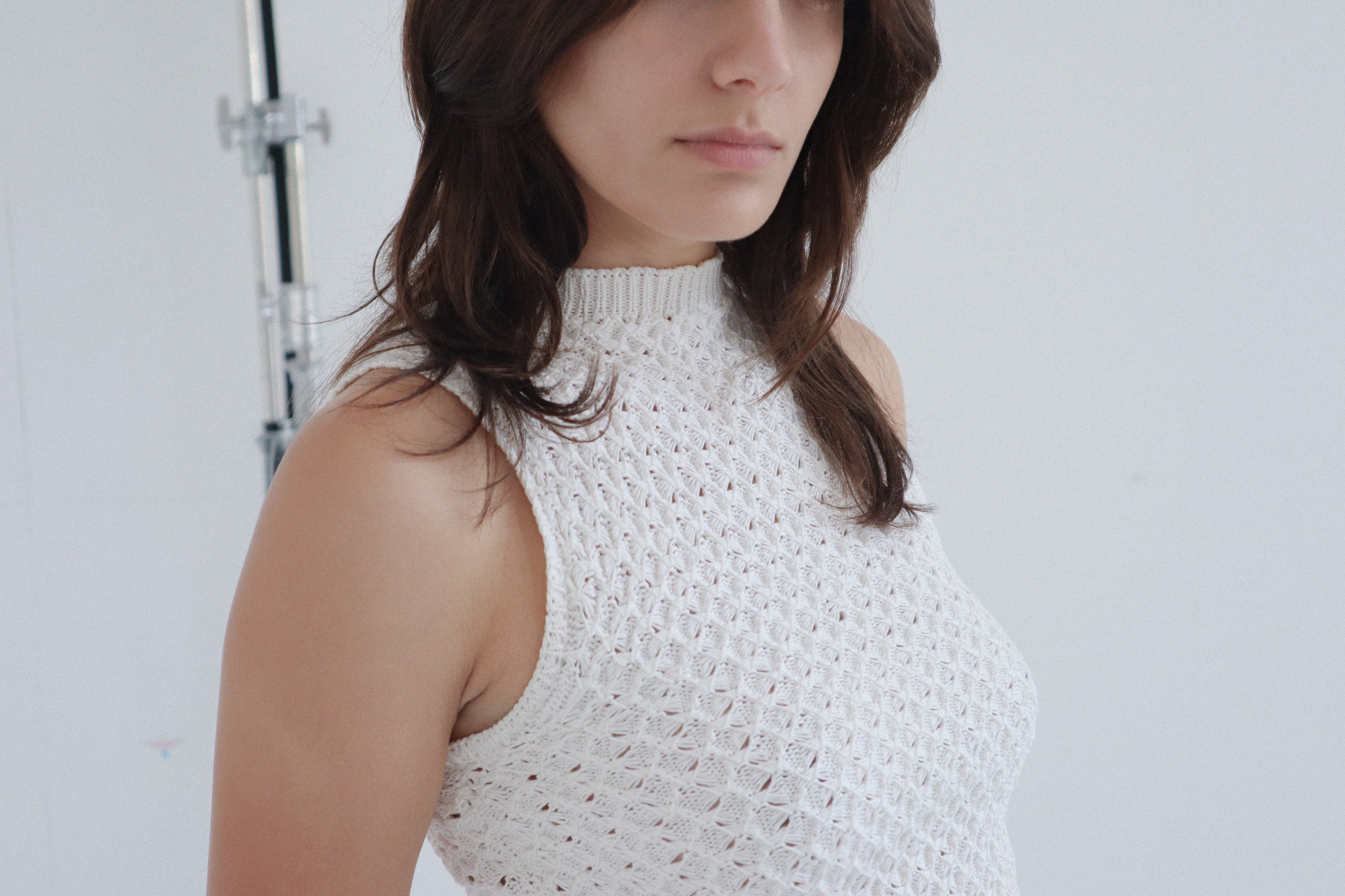 A model wearing the noa top in a white background. 100% white cotton knit.