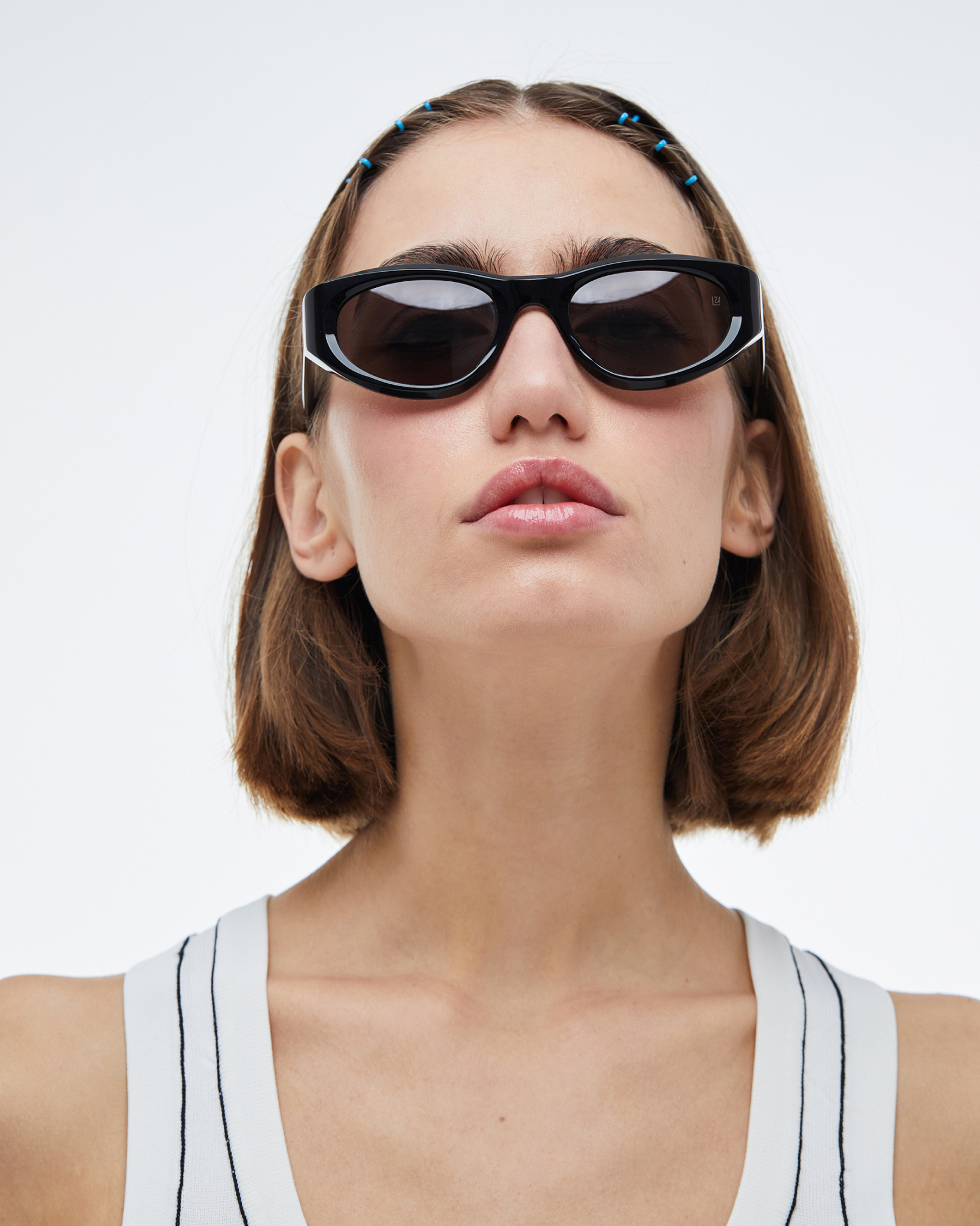 Woman wearing black sustainable sunglasses with a plain white background. Made from 100% Mazzuchelli Bio-Acetate.