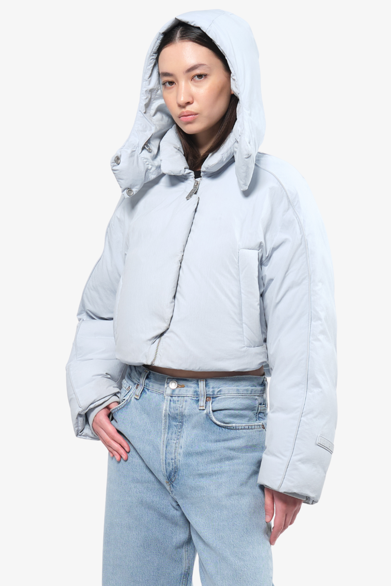 Model wearing a crop puffer in a white background. 100% made from recycled fabric.