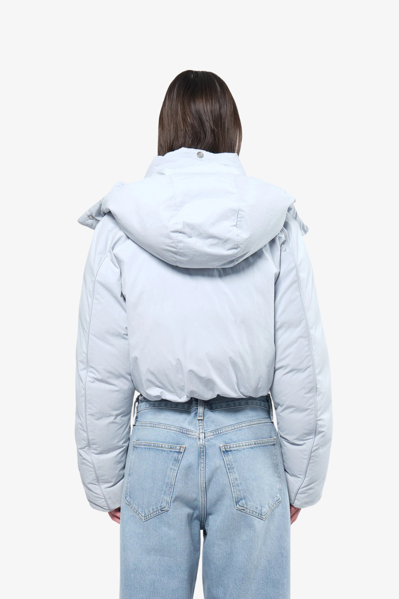 Model wearing a crop puffer in a white background. 100% made from recycled fabric.