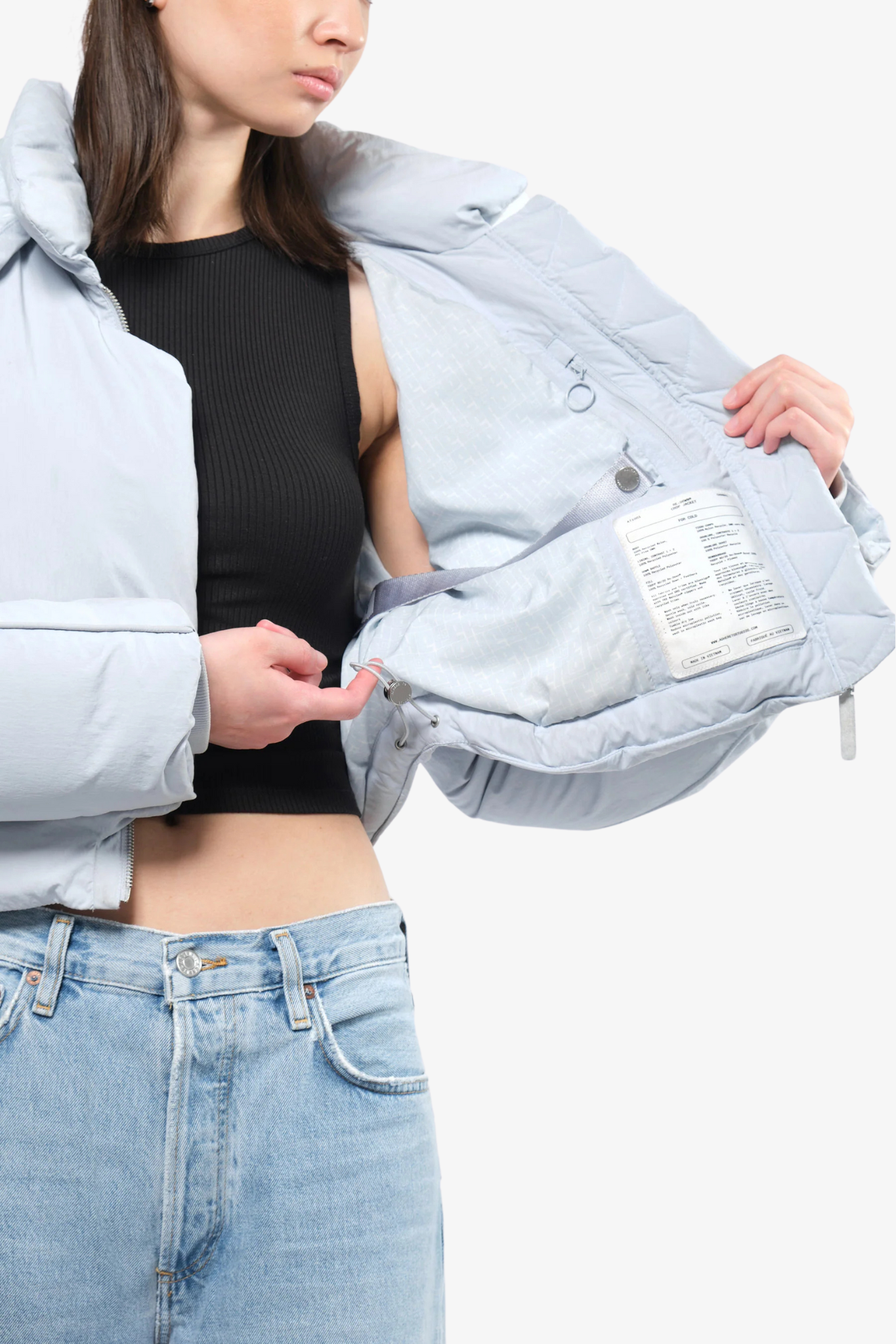 Model wearing a crop puffer in a white background. 100% made from recycled fabric.