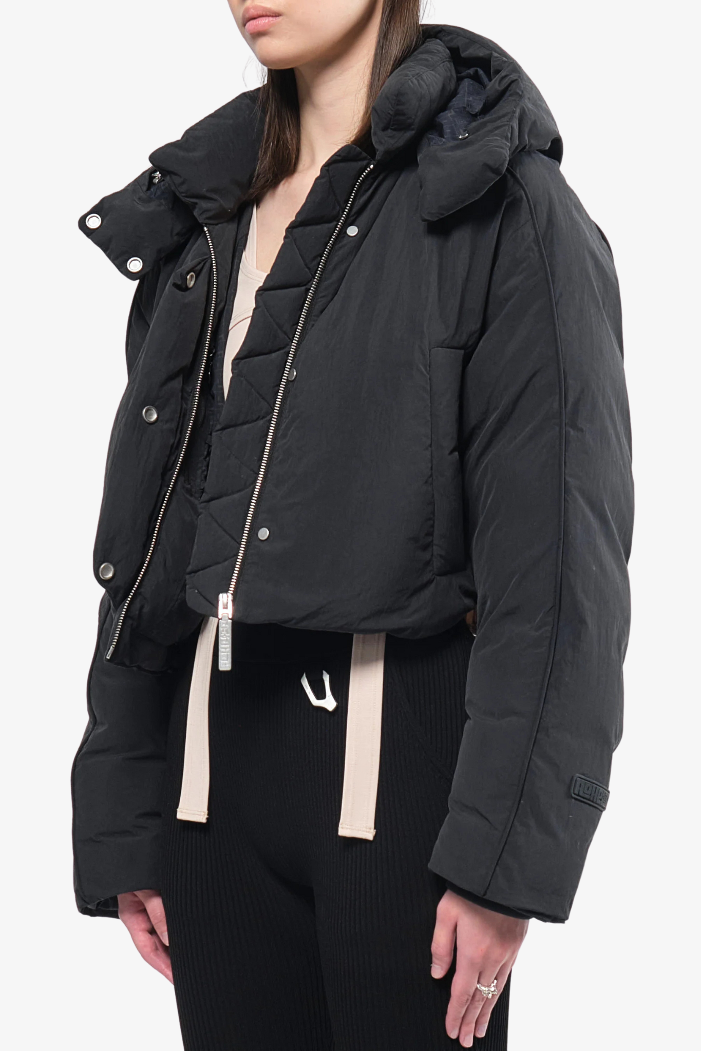 Model wearing a crop puffer jacket in a white background. 100% made from recycled fabric.