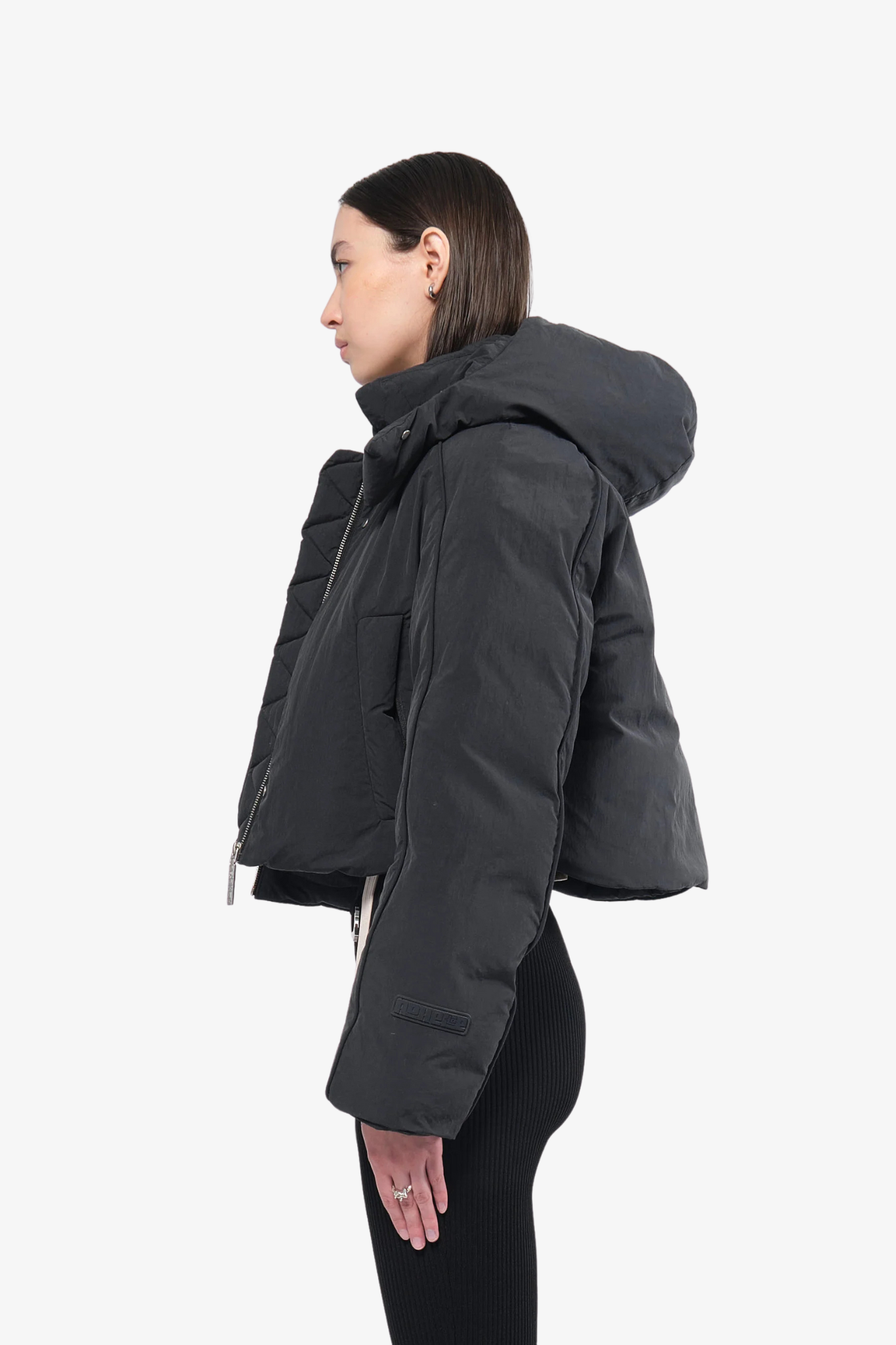 Model wearing a crop puffer jacket in a white background. 100% made from recycled fabric.