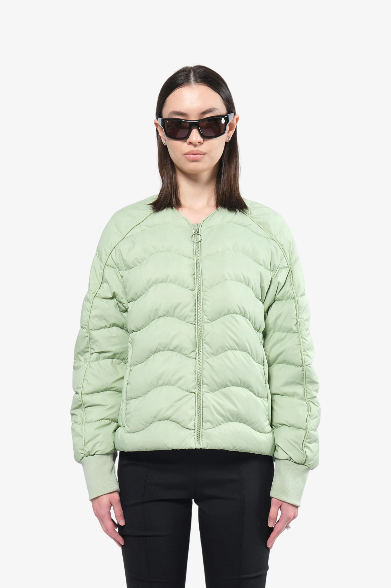 Model wearing a light puffer jacket in a white background. 100% made from recycled fabric.