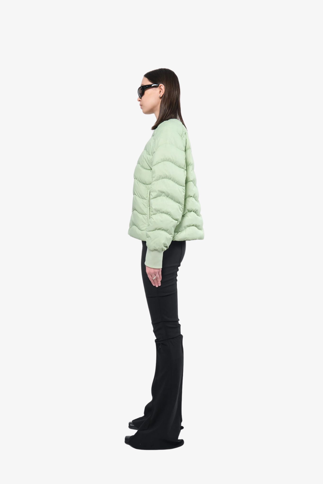 Model wearing a light puffer jacket in a white background. 100% made from recycled fabric.
