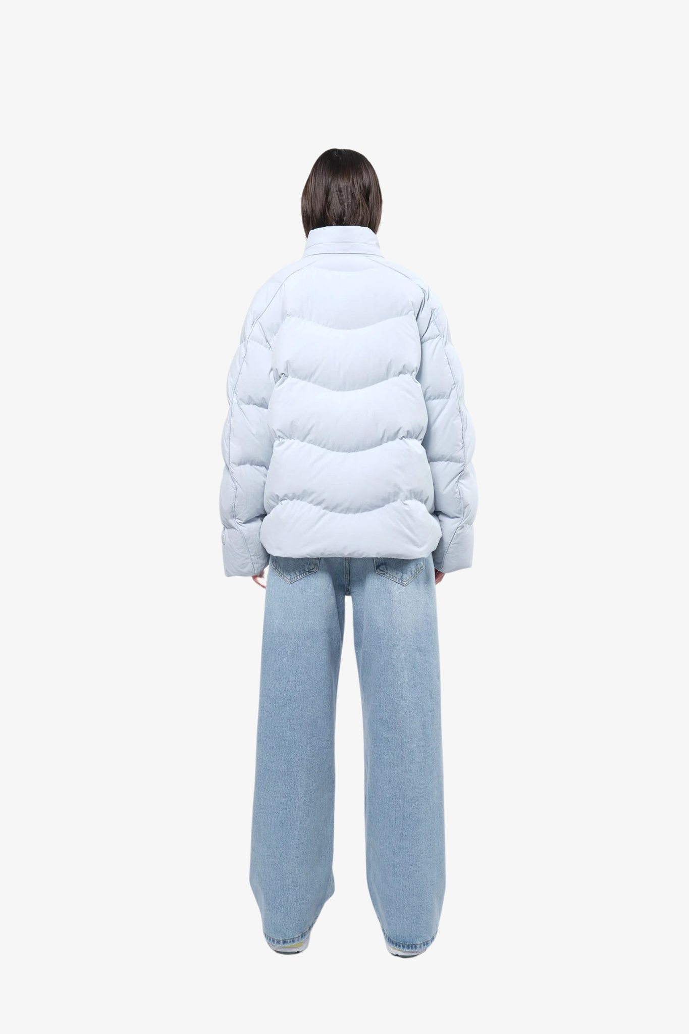 Model wearing a puffer jacket in a white background. 100% made from recycled fabric.