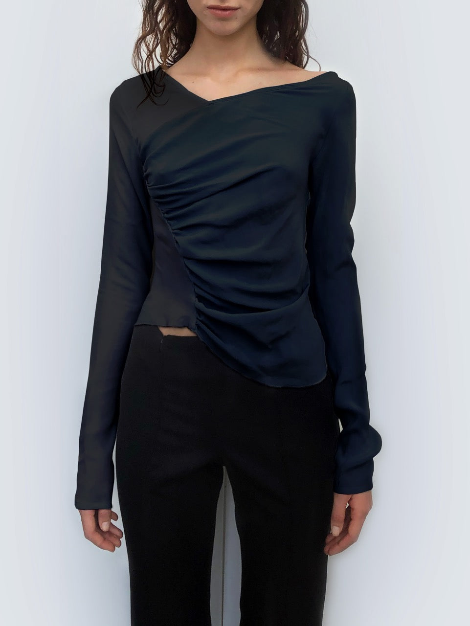 Woman wearing a black sustainable silk long-sleeve top against a plain background