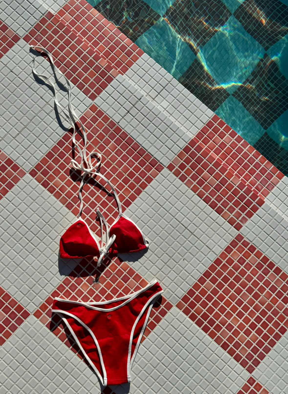 Red bikini set made from hemp and organic cotton on a tiled poolside floor