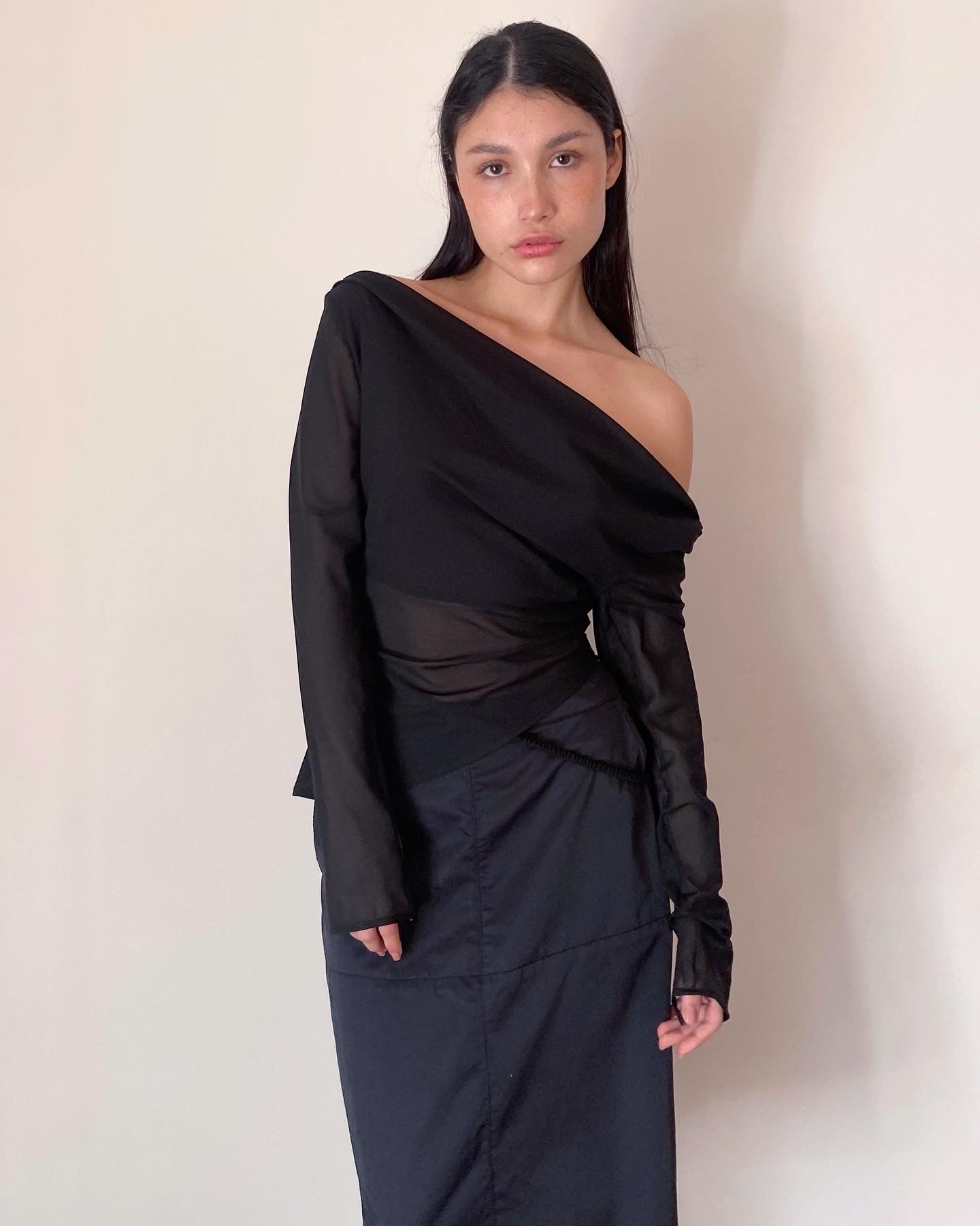 Woman wearing a black one-shoulder top against a plain background. Made from 100% recycled material.