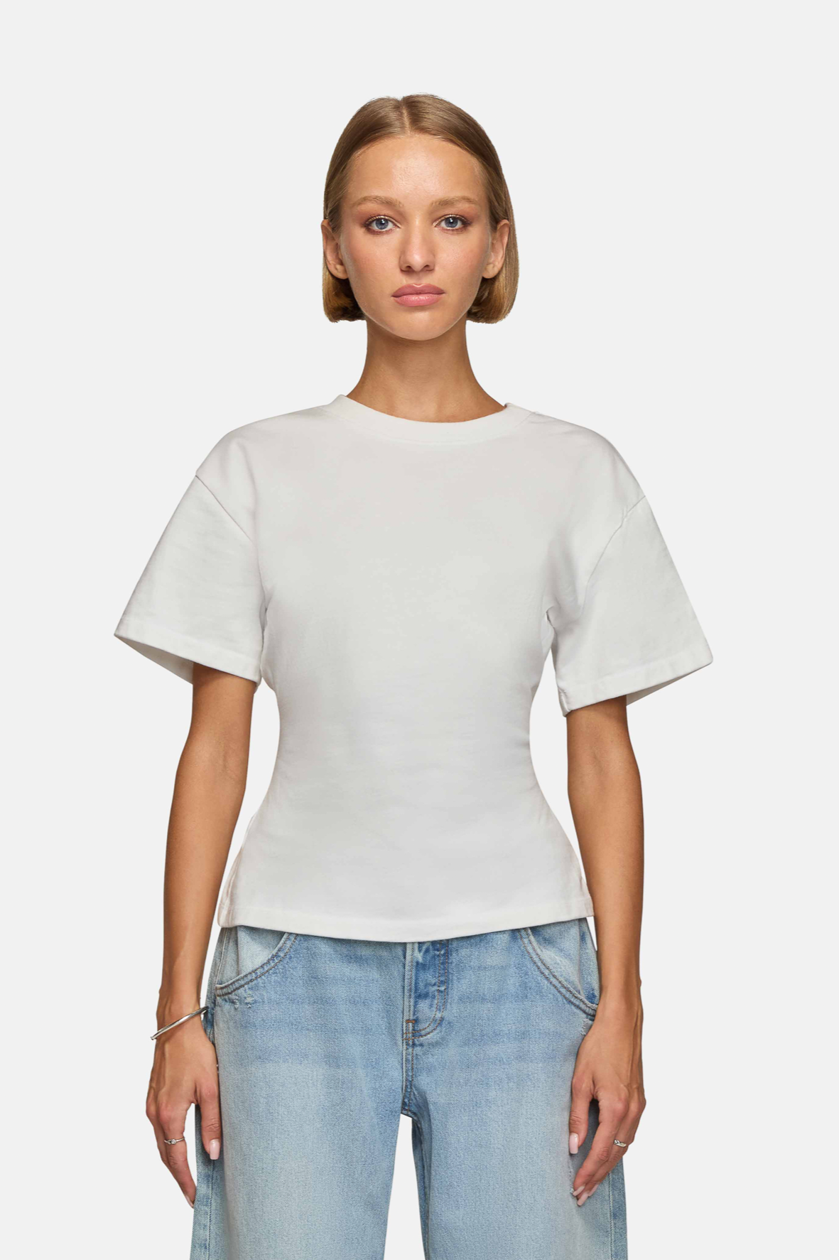 Woman wearing a white, oversized tee with short sleeves and a round neckline. Made from 100% Organic Cotton.