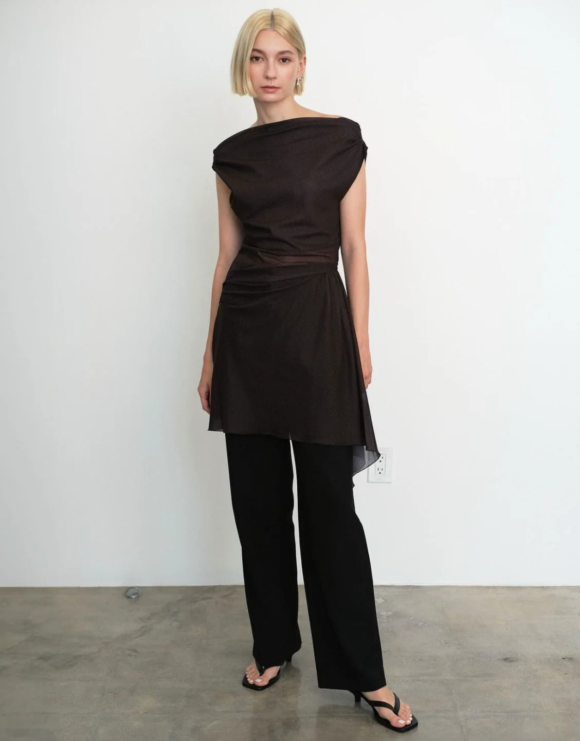 Woman wearing a black dress and black pants against a plain background. Made from sustainable deadstock materials.