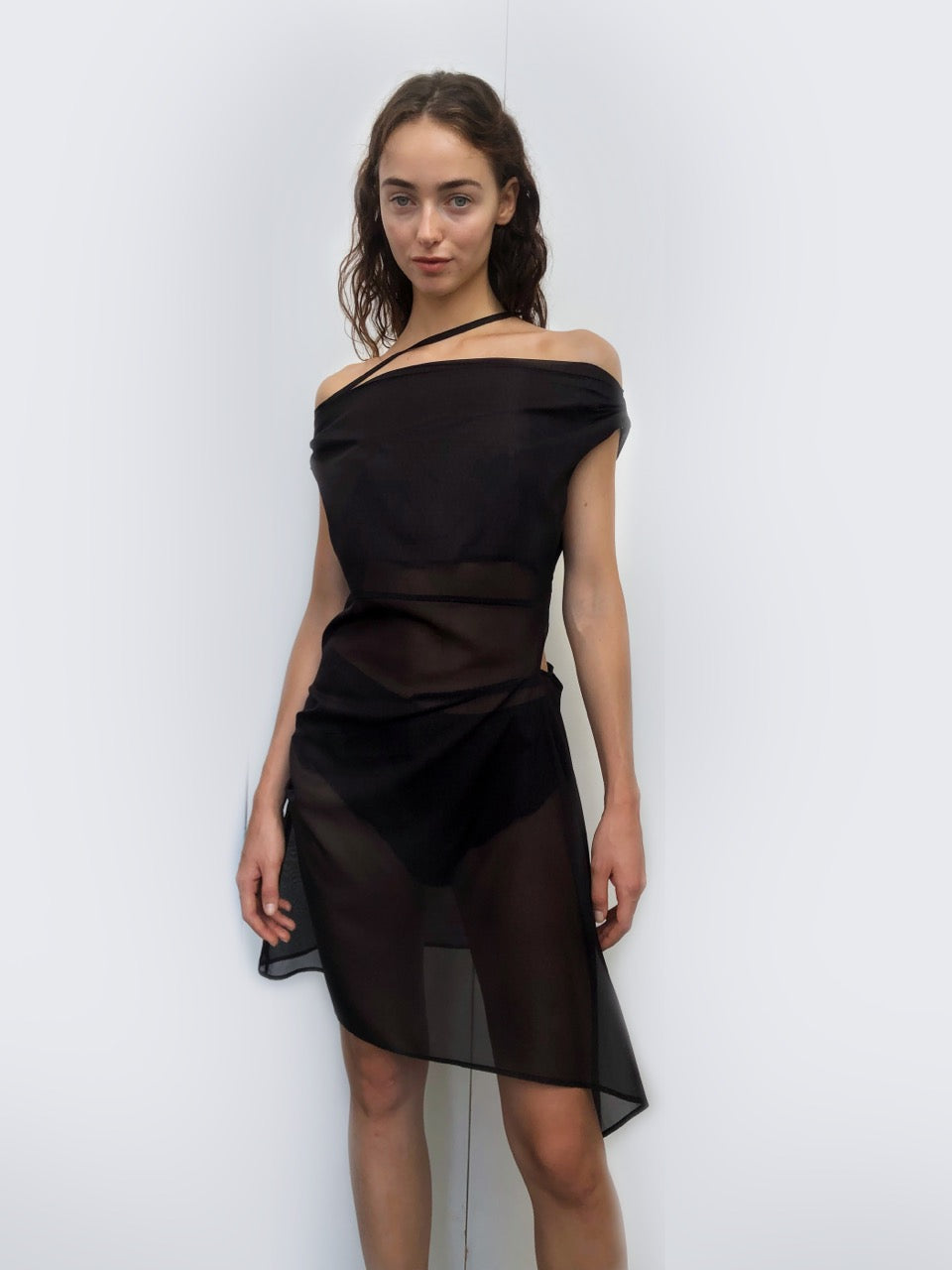 Model wearing a sheer black dress against a white background. Made from sustainable deadstock materials.