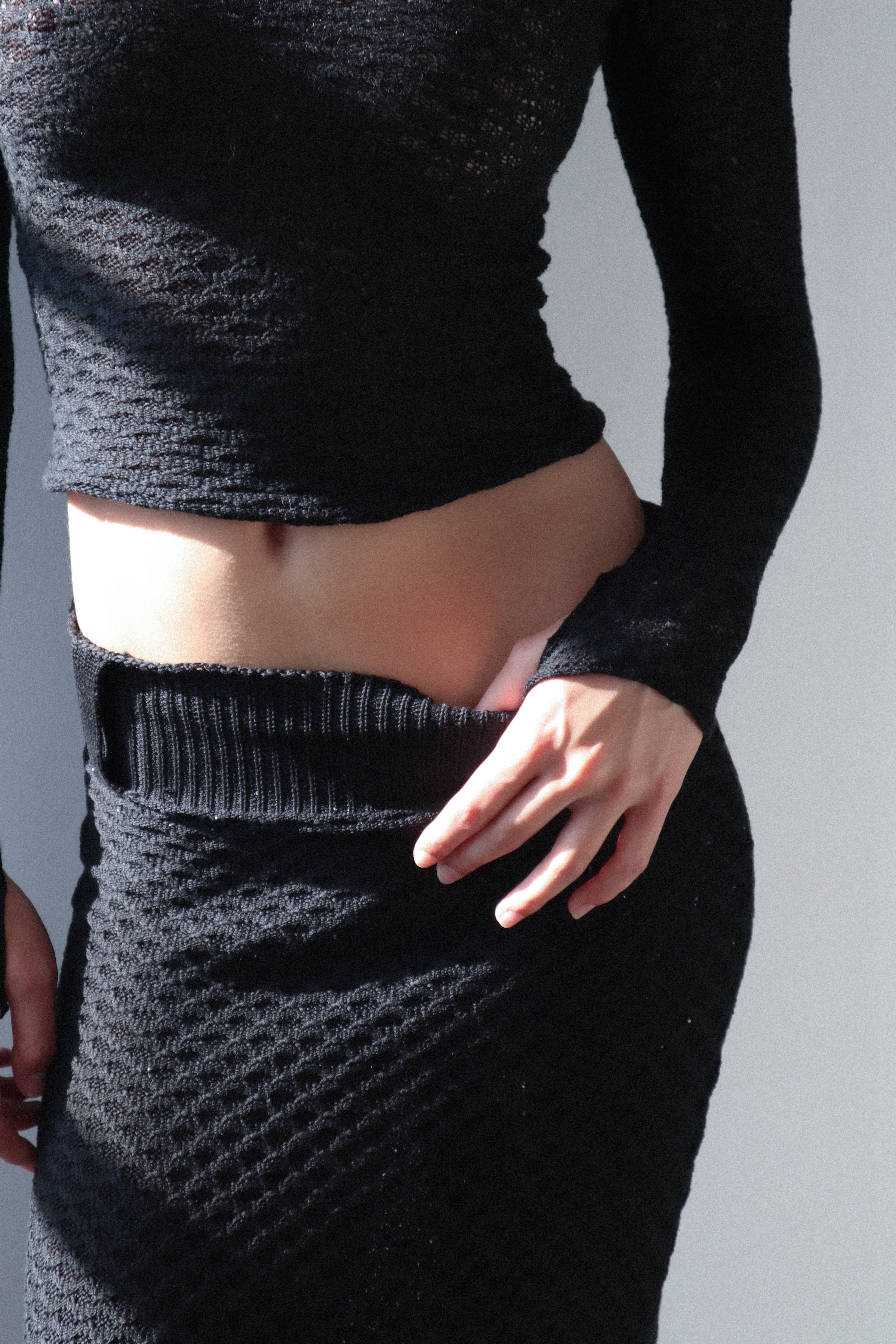 A model wearing the slye top in a white background. 100% black cotton knit.