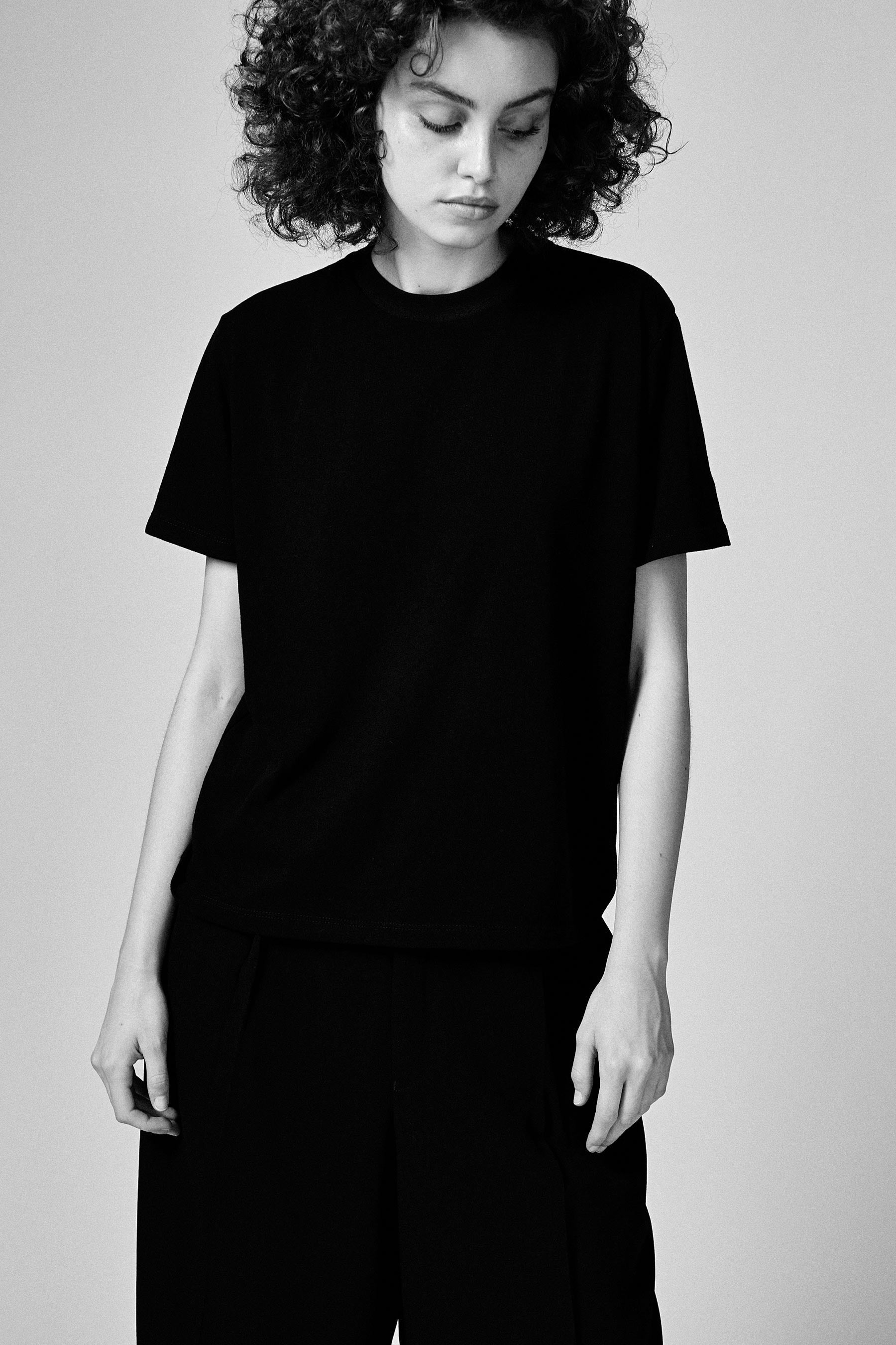A model wearing the black T101 classic tee in a white background. 100% made from organic grown cotton.