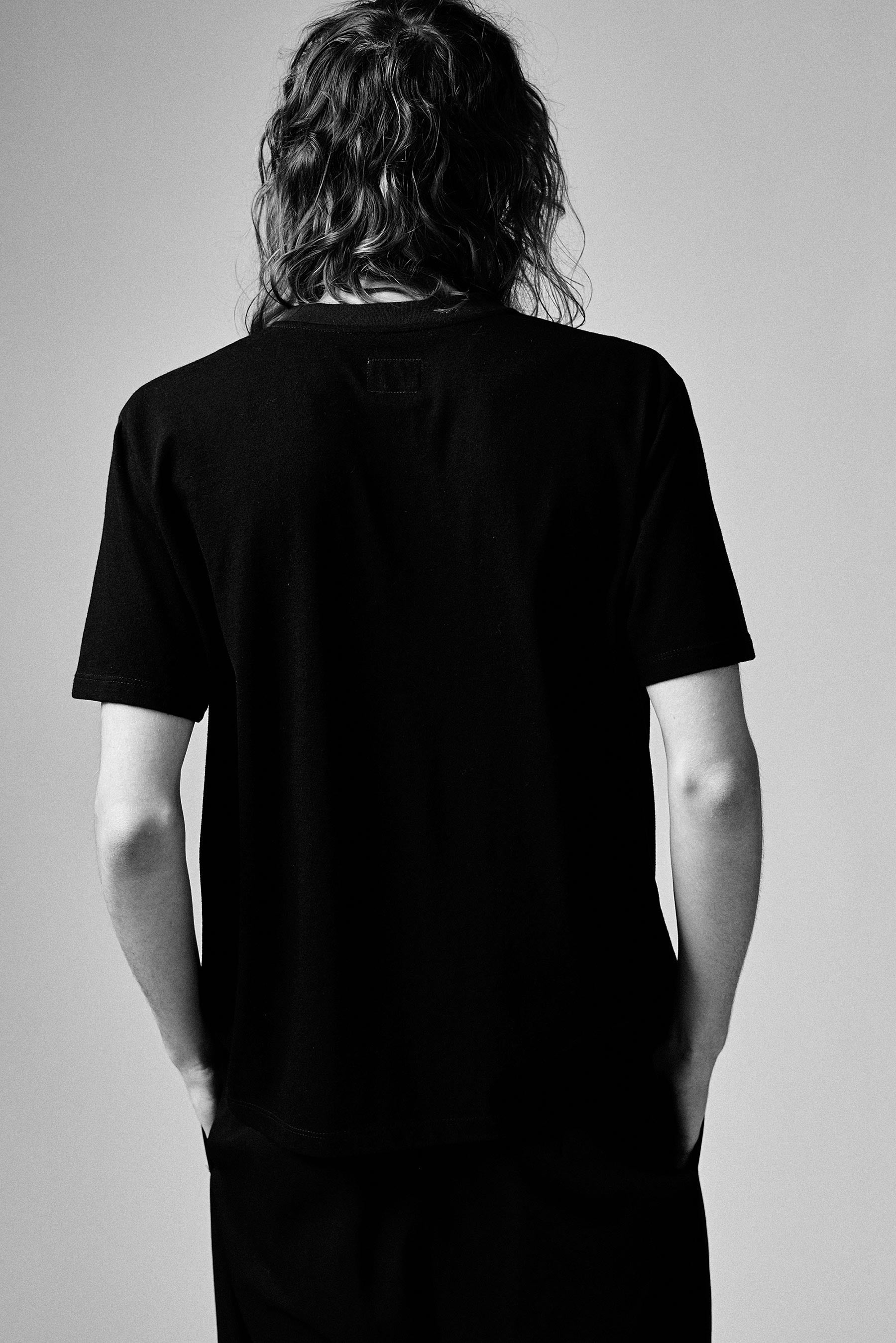 A model wearing the black T101 classic tee in a white background. 100% made from organic grown cotton.