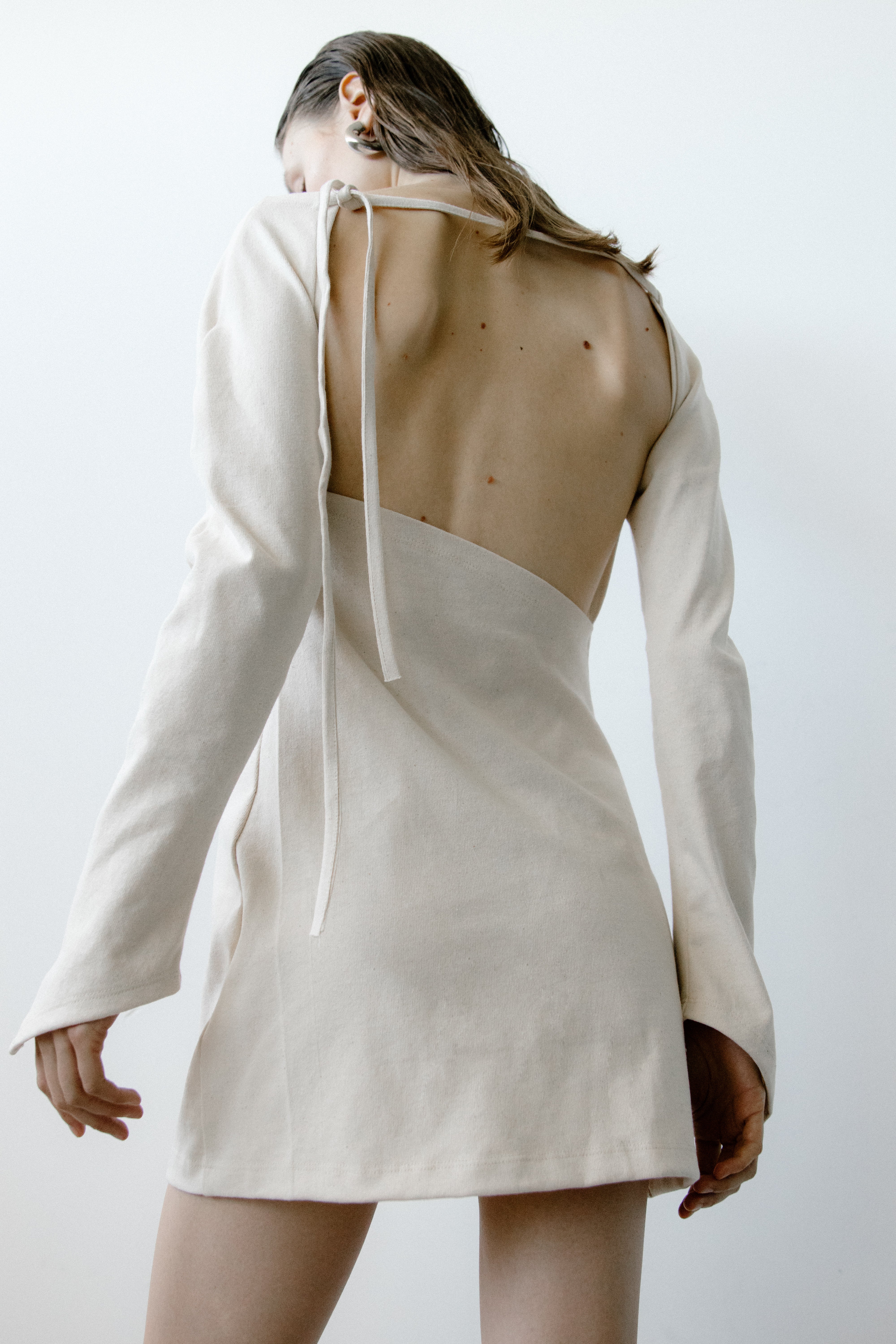 A model wearing the triangle mini dress in a white background. 100% made from organic cotton.