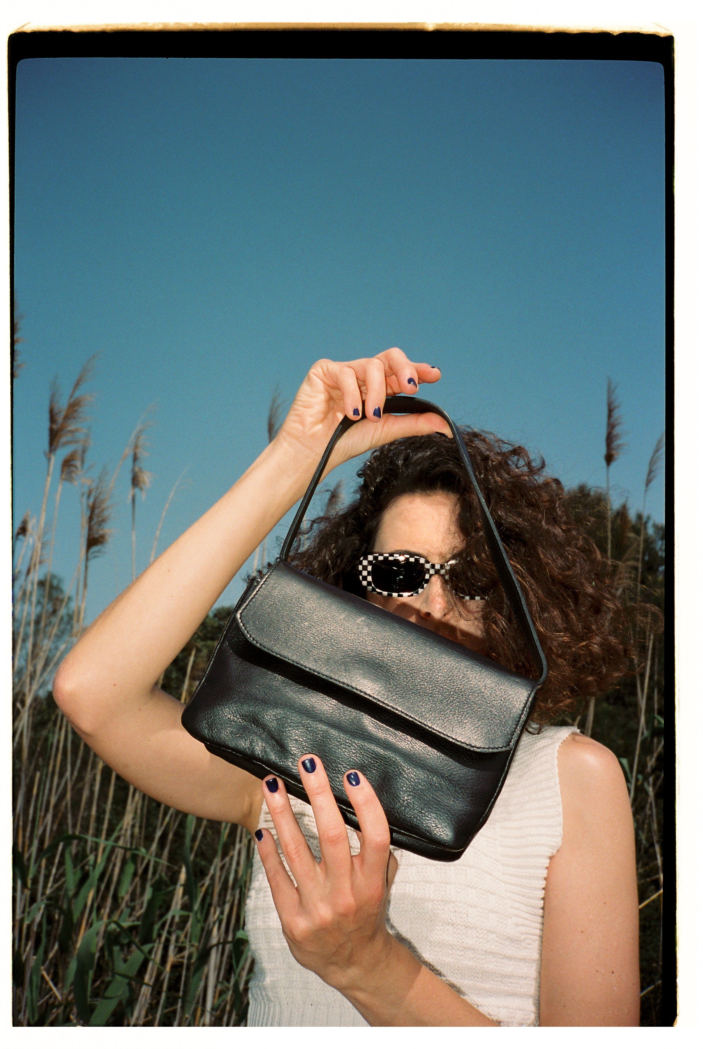 A model wearing the babe black matte bag in an aesthetically background. 100% made from deadstock leather.