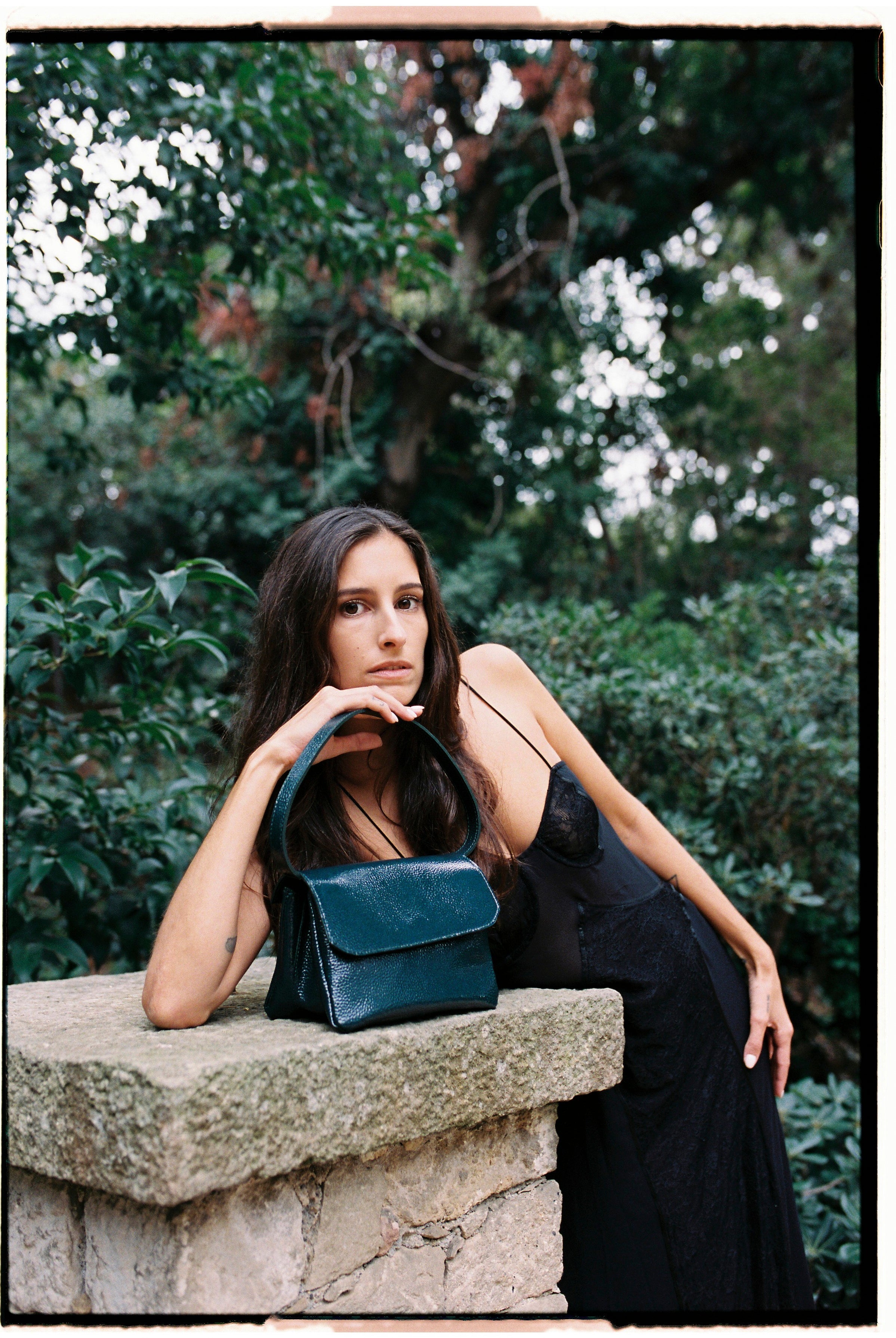 A model with the babe forest green bag in an aesthetically background. 100% made from deadstock leather.