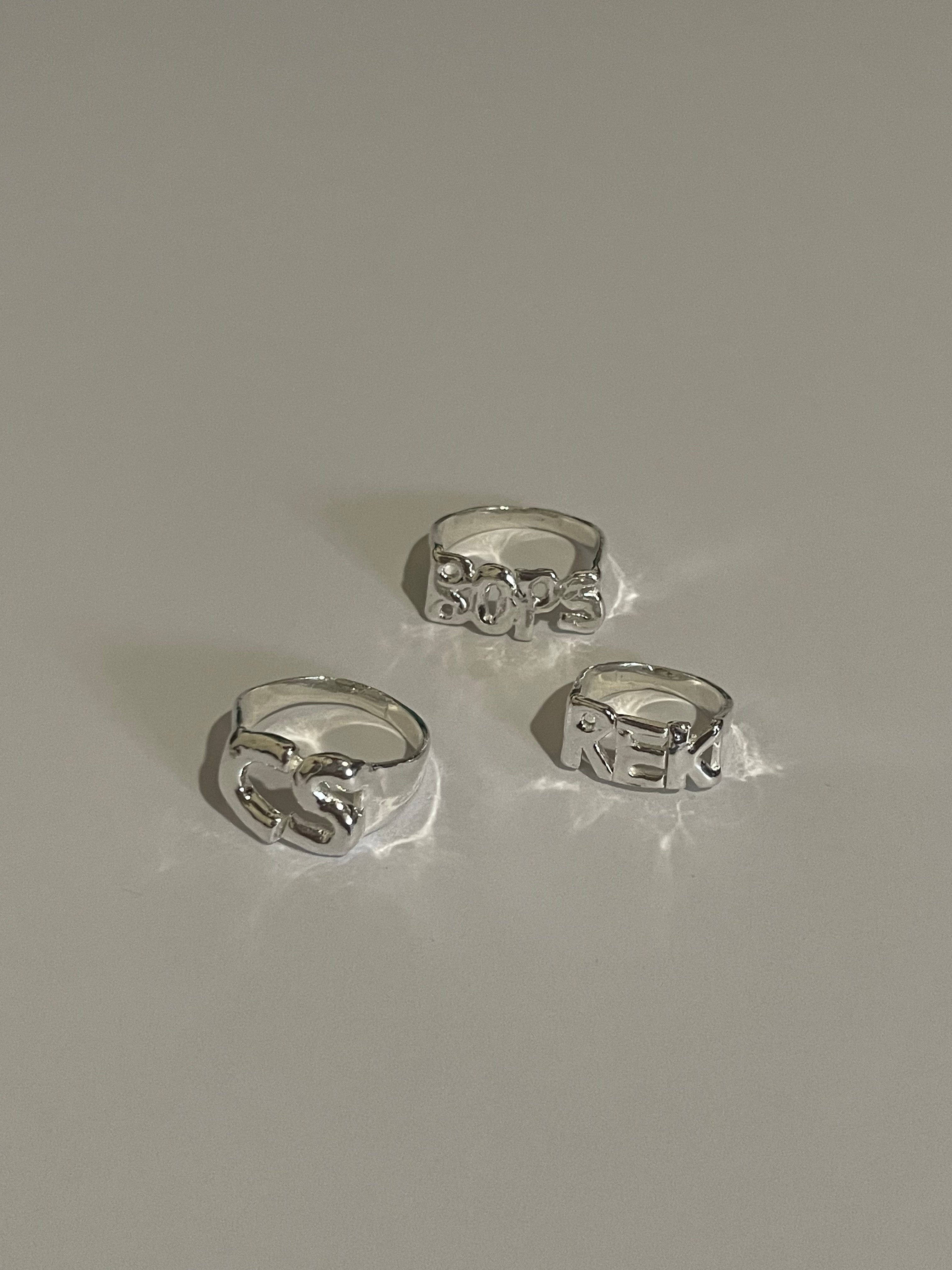 The custom letter ring in a white background. Made from 100% recycled metals and lab created gemstones.