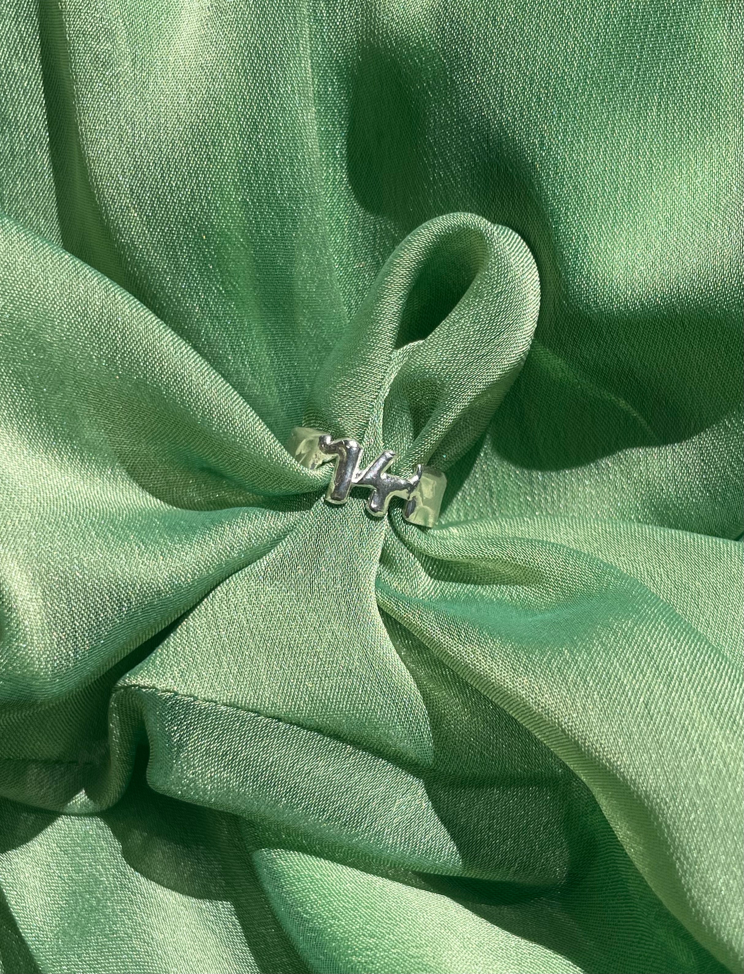 The custom number ring in a green background. Made from 100% recycled metals and lab created gemstones.