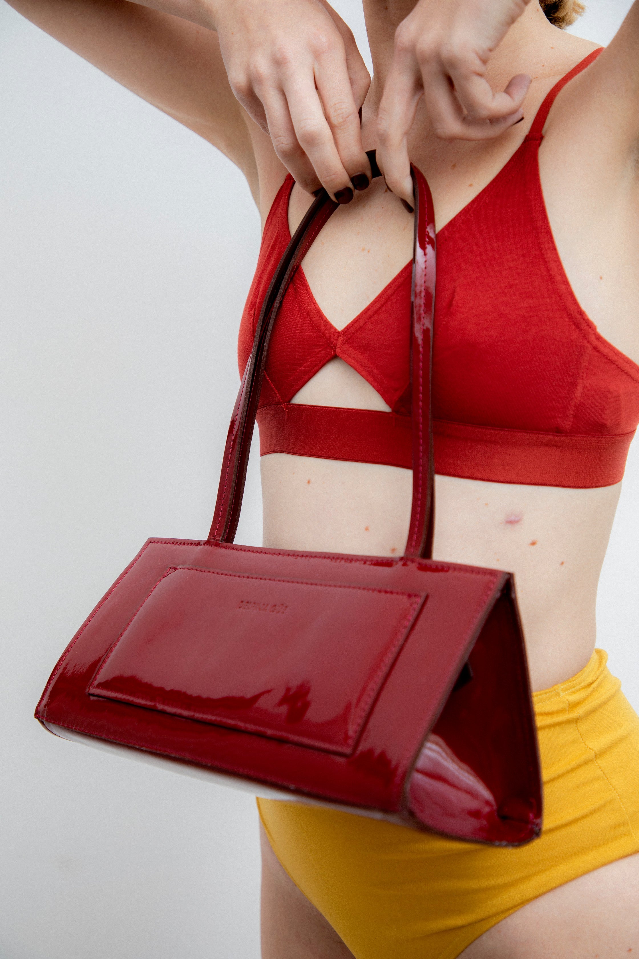 A model wearing the hotdog burgundy bag in a white background. 100% made from deadstock leather.