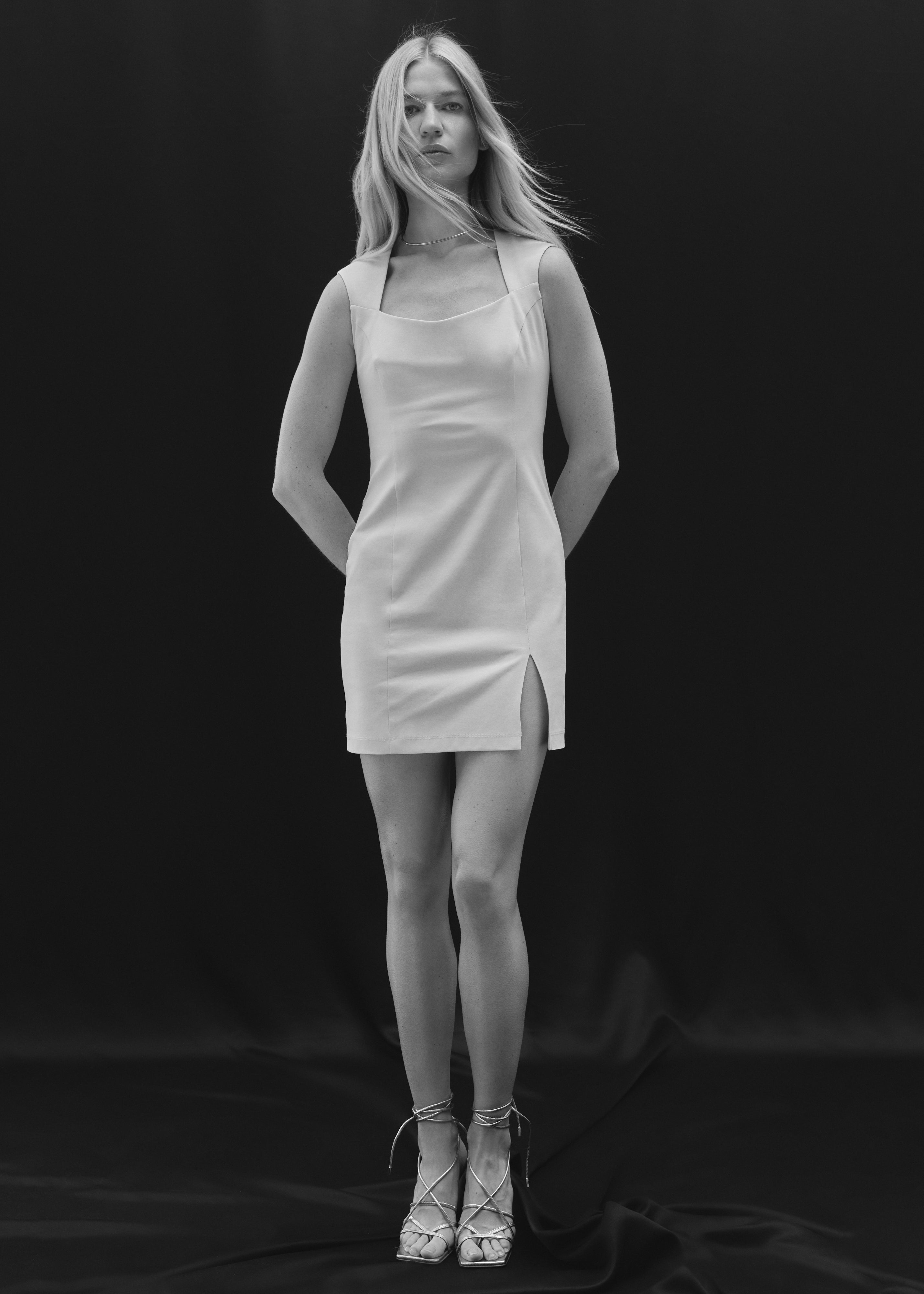 A blond model posing in a light beige mini dress with a front slit by Her Cipher