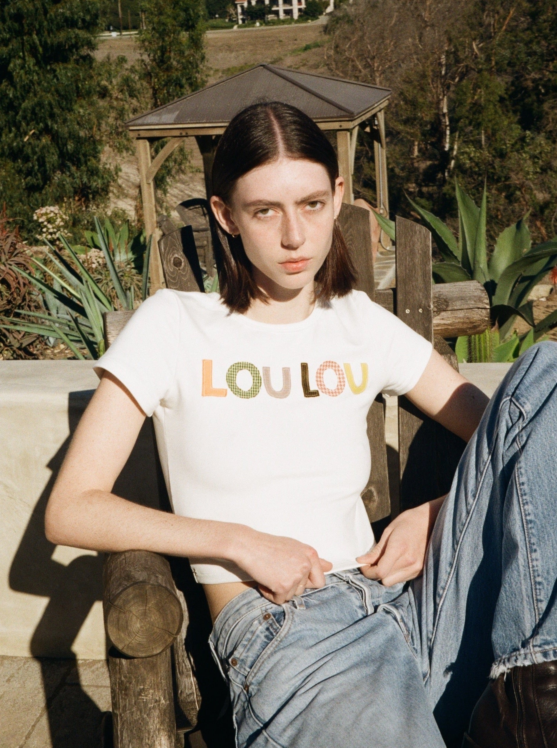 A model wearing the custom baby tee in a outdoor background. Made from certified organic cotton and deadstock.